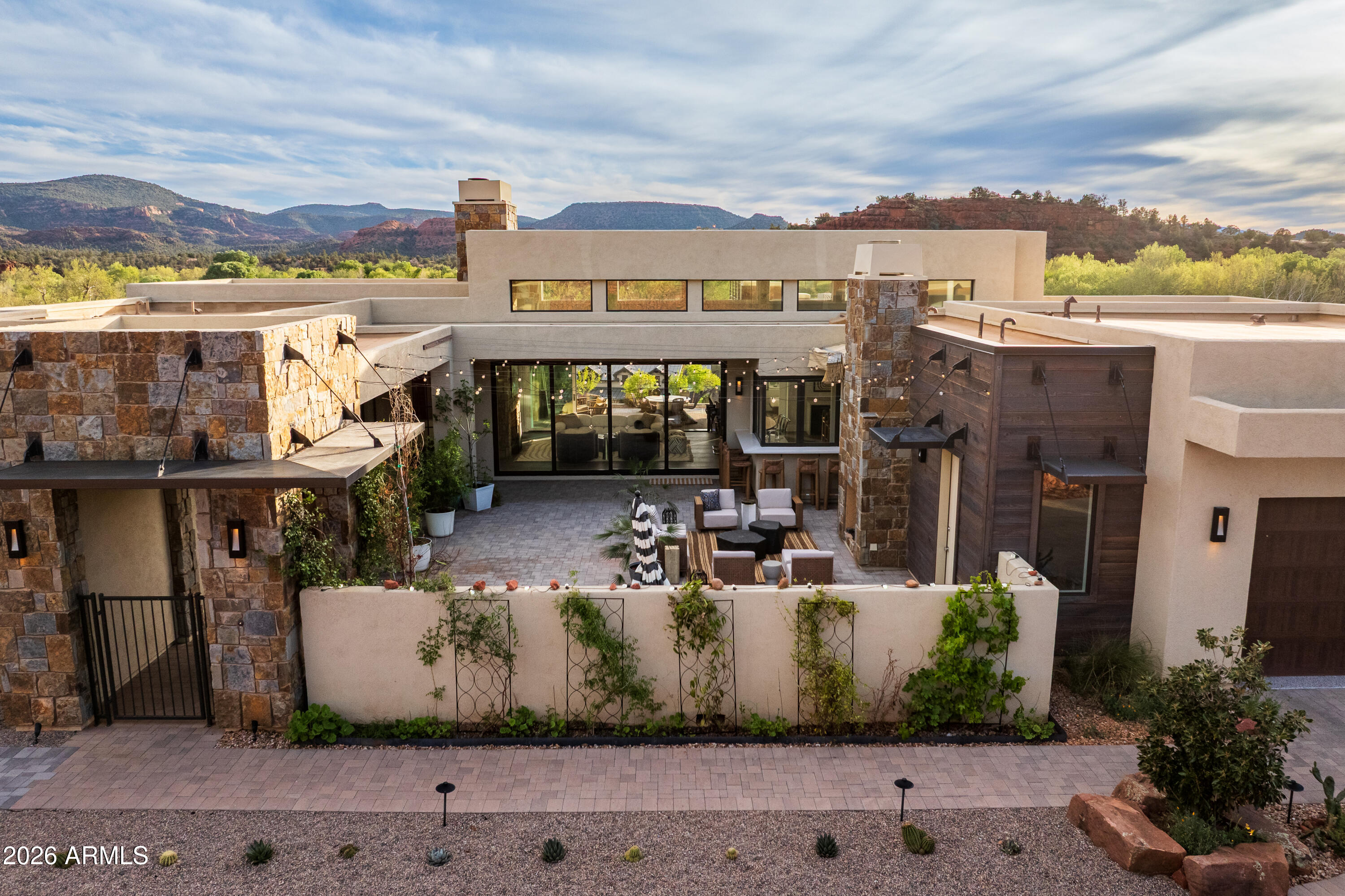 Set across a rare double lot, unfolding between rock and sky, where architecture settles naturally into Sedona's landscape. Outdoor living is anchored by a sculpted pool and spa, with layered spaces for gathering or quiet retreat, organized around a shaded pavilion, framed by open land and red rock views. The transition indoors is seamless, with expansive openings that draw the landscape in. In the main living space, volume and light define the experience, with 16-foot ceilings and clerestory windows introducing a soft, ambient glow. Clean lines, grounded materials, and a striking stone fireplace create a setting both expansive and composed. Above, a rooftop terrace offers an elevated vantage point for sunset, stargazing, and uninterrupted views of Sedona's surrounding beauty. Broker Owner Beyond the primary living spaces, the scale of the double lot allows the property to function with a level of flexibility rarely found in Sedona. Outdoor areas unfold as a series of distinct zones, each with its own orientation and purpose. The pavilion anchors one of these spaces, while others remain open to the landscape, preserving long sightlines and a strong connection to the natural terrain. Just beyond the pool area, a private trail extends nearly 100 yards into the junipers, following natural animal paths and offering a quiet, immersive connection to the land.

The home's layout is both intuitive and adaptable. It includes three full-size bedrooms, complemented by a generous office that can easily serve as an additional sleeping area when needed. The owner's entry has been fully upgraded to function as a practical transition space, ideal for storing hiking gear, outdoor equipment, and kitchen overflow. A large laundry room adds further flexibility, with enough space to accommodate projects, storage, or utility use beyond its primary function.

Interior circulation maintains clear sightlines while allowing for separation where needed. Clerestory windows bring in consistent natural light while preserving privacy and uninterrupted wall space. Material selections emphasize durability and restraint, with finishes chosen to age well and remain visually quiet over time. The stone fireplace anchors the main living space, balancing the openness created by the volume above.

The landscaping extends the livability of the property, blending cultivated and native elements. Multiple fruit trees--including nectarine, peach, apple, and plum--are complemented by a row of berry bushes and a curated collection of flowering cacti integrated into the natural desert palette.

Located within Sedona Ranch at Oak Creek, the property also benefits from a rare connectivity advantage: direct access to the Village of Oak Creek via Verde Valley School Road and to West Sedona via Red Rock Loop Road. This dual access is both highly practical and unique to this exclusive community, offering flexibility in daily movement while maintaining the sense of separation and quiet that defines the setting.