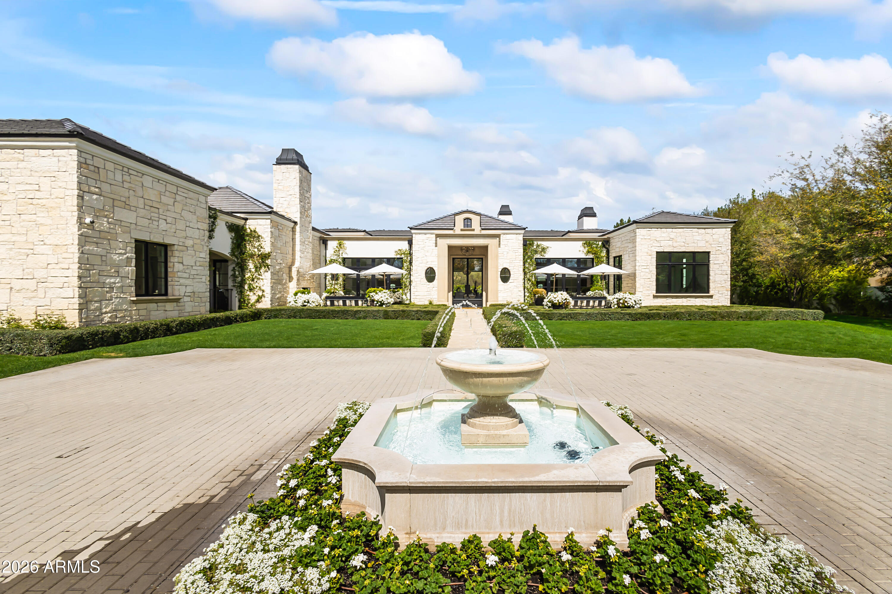 Tucked behind gates on a quiet cul-de-sac in the heart of Paradise Valley, this rare nearly 1.5-acre estate offers exceptional privacy, timeless architecture, and resort-style living. Welcomed by a sparkling fountain, the home's sophisticated design features soaring ceilings, designer lighting, and walls of sliding glass and French doors that fill the interiors with natural light. Designed for seamless indoor-outdoor living, the expansive great room showcases a gas fireplace and retractable wall of glass opening to the breathtaking backyard. Entertain effortlessly with a formal dining room and elegant living room complete with a wet bar and retractable wall of windows to enjoy Arizona weather. The chef's kitchen is the heart of the home, featuring double islands, premium appliances, multiple ovens, wood-beamed ceilings, an eat-in dining area, and a fully equipped butler's pantry and prep kitchen. The luxurious primary suite offers a private retreat with its own fireplace, direct backyard access, dual custom closets, dual vanities, a freestanding soaking tub, oversized walk-in shower, and separate toilets. The resort-inspired backyard features a custom heated pool and spa, outdoor BBQ, outdoor fireplace, expansive covered and uncovered patios, and lush manicured grounds framed by mature trees and landscaping. Additional highlights include a dedicated expansive office with french doors and exterior access and a spacious 4-car garage. Ideally located in the highly sought-after "3 C's" school district and near Arizona's world-class resorts, golf, hiking, fine dining, and upscale shopping.