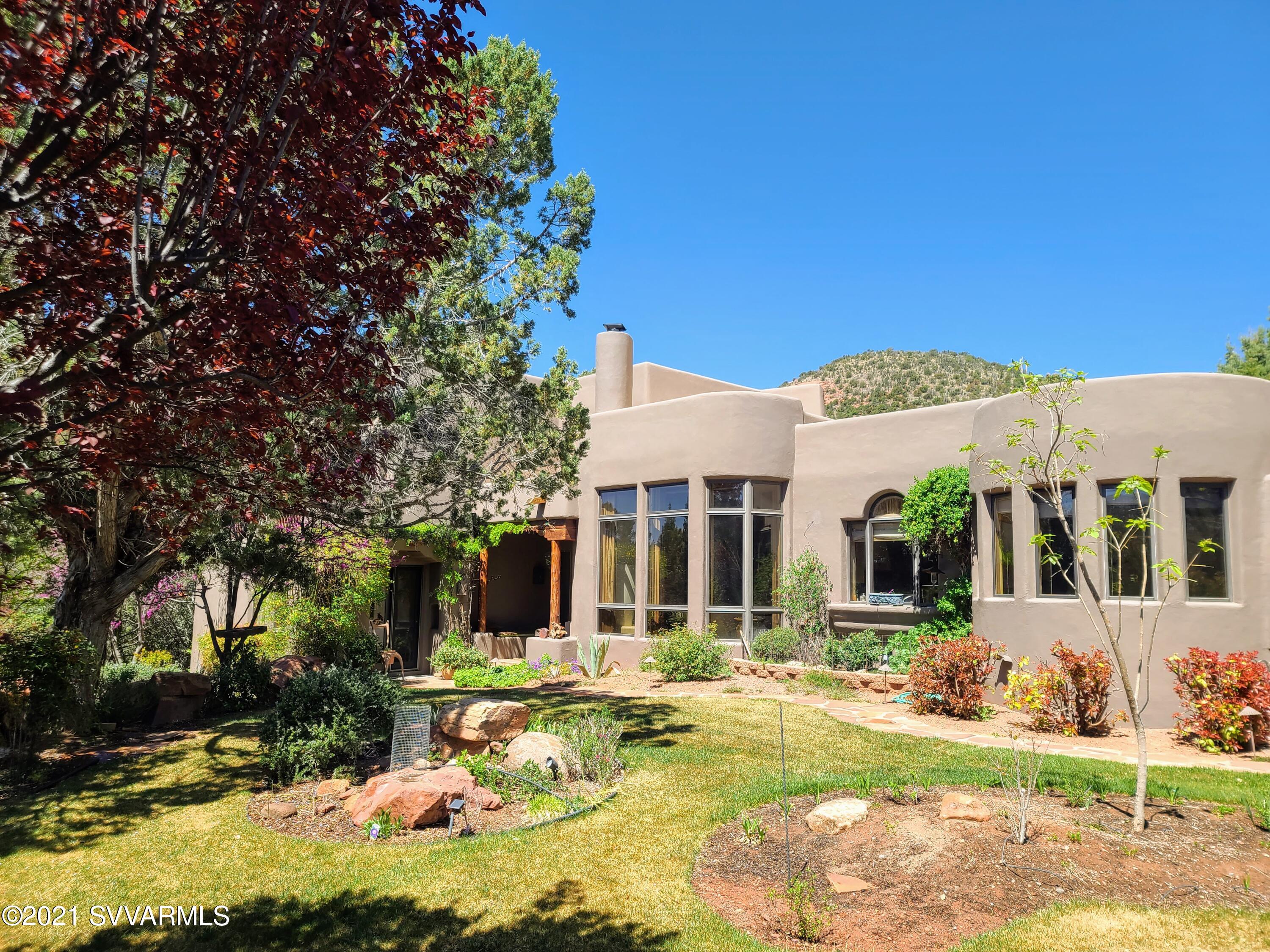 You are invited . . . to experience an incredibly private setting for this inviting, custom Southwest home! Step into an oasis & experience a brilliant Santa Fe style design, executed w/ meticulous attention to detail & craftsmanship.  Details include: Grapestake wood ceilings, mill sawn Poplar cabinetry, radius plaster, custom corbels, rafters, solid Pine & Poplar wood flooring, Saguaro ribbed solid 3 inch doors, 2'' X 10'' exterior walls with extra insulation & more! Main house with 3 bedrooms and 3 bathrooms plus additional separate studio spans over 3100 sq. ft. & is graced by beautiful landscaping; multiple water features, patios & gardens, arches, antique iron gates & fully fenced yard. Beautiful red rock views. Fabulous chef's kitchen w/ Viking & Sub Zero. A must see! See Documents.