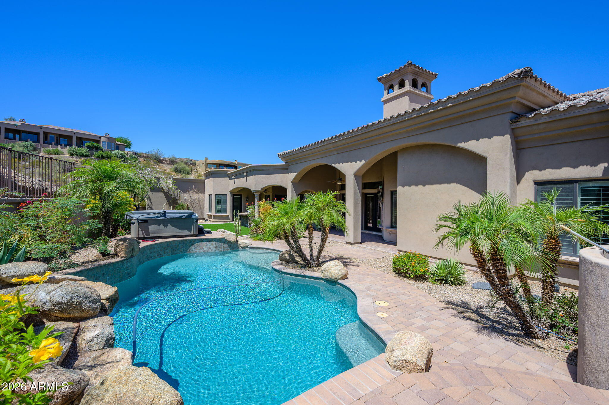 Set on an expansive hillside homesite in the sought-after Ahwatukee Foothills, this exceptional custom estate offers refined single-level living with sweeping mountain vistas and an unmatched blend of luxury and livability. Spanning over three-quarters of an acre, the property is designed to impress at every turn, from its grand living spaces to its resort-style outdoor amenities.  Inside, the home features five spacious bedrooms and four and a half baths, thoughtfully arranged for both everyday comfort and upscale entertaining. Elegant gathering areas flow effortlessly from the formal living and dining rooms into a stylish wet bar and an inviting family room anchored by striking indoor/outdoor stone fireplaces. (More..) Custom details and curated finishes create a warm yet sophisticated atmosphere throughout. 
 
The chef's kitchen is as functional as it is beautiful, appointed with premium appliances, custom cabinetry, a walk-in pantry, prep sink, and generous stone surfaces ideal for hosting or daily use. The primary suite offers a private retreat, complete with a spa-inspired bath, soaking tub, oversized walk-in shower, and a substantial closet designed to accommodate any wardrobe.

Each additional bedroom is well-appointed with its own en-suite bath and walk-in closet, while a flexible bonus room, perfect for an office or guest space and includes direct access to a private patio.

Outdoor living is elevated with a covered patio, built-in barbecue, sparkling pebble-finish pool, mature landscaping, and a rooftop deck that captures breathtaking panoramic views. Car collectors and hobbyists will appreciate the impressive approximately 2,000-square-foot garage, built to accommodate up to eight vehicles and outfitted with extended bays, extensive storage, and thoughtful utility features.

Conveniently located near highly regarded schools, scenic hiking trails, golf courses, and with easy access across the Valley, this one-of-a-kind residence delivers a rare opportunity to own a truly elevated desert lifestyle.