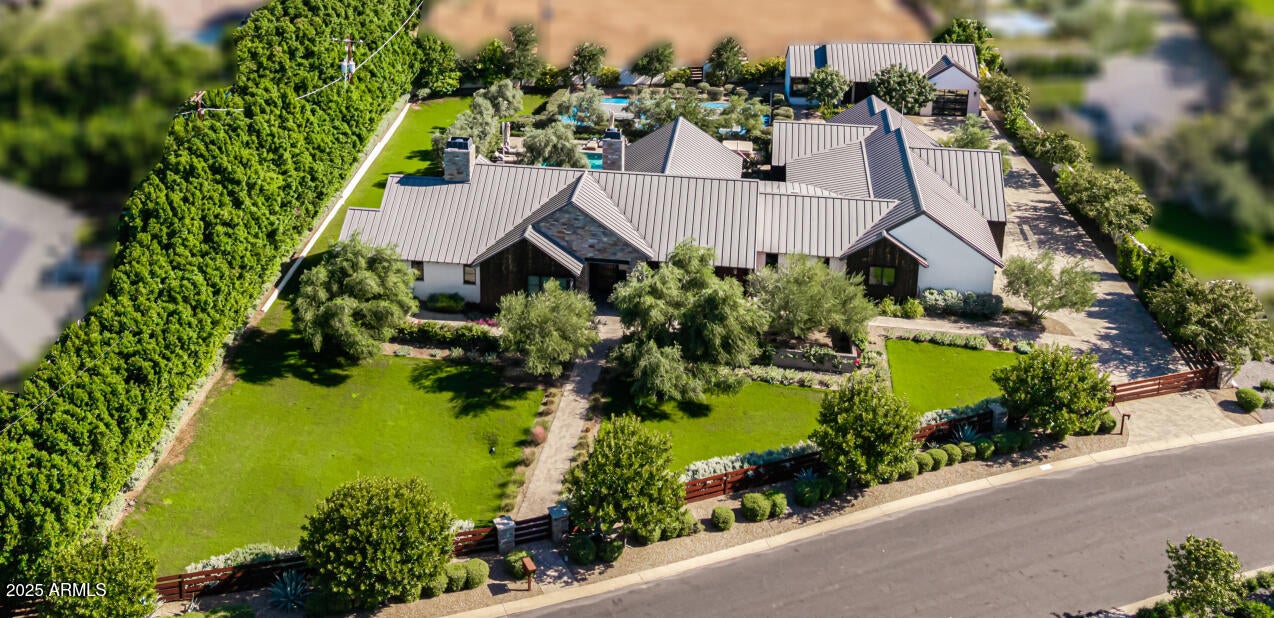 A combined total of nearly 6,000 sq ft of Luxury Arcadia Estate . Main house has  
4,933 Sq Ft  and Guest house with 854 Sq Ft with its own garage | Approx. 1 Acre | 5 Bedrooms | 5 Full Bathrooms / 2 Half Baths | Detached Guest House | 5-Car Garage | Pool | Pickleball Court
Nestled in the heart of Arcadia Proper, one of Phoenix's most prestigious neighborhoods, this stunning modern estate is situated on nearly an acre, this gated residence captures breathtaking Camelback Mountain views and offers unparalleled indoor-outdoor living.
The main residence showcases soaring cathedral ceilings with exposed beams, expansive glass doors, and designer finishes throughout. The chef's kitchen is a showpiece, featuring quartz countertops, a large island with breakfast bar, two sinks, custom cabi full-height tile backsplash, and an oversized butler's pantry.
The primary suite is a private retreat complete with a gas fireplace, direct patio access, an impressive custom closet with center island and washer/dryer, and a spa-inspired bathroom featuring dual vanities, a walk-in rain shower, and soaking tub.
The home's layout includes three ensuite guest bedrooms, a den/office, two half baths, and a wet bar with refrigerated drawers and a fireplace in the family roomperfect for entertaining.
Step outside to your resort-style backyard with a sparkling heated salt water pool, gas fire pit, and a professional pickleball court surrounded by lush landscaping and mountain vistas. A detached 863 sq. ft. guest house with its own garage provides ideal accommodations for visitors or multi-generational living. Additional features include a five-car garage (four-car main plus one-car guest), epoxy flooring, built-in cabinetry, and ample guest parking for nearly a dozen cars on the gated, paved driveway. Located just minutes from the best of Phoenix and Scottsdale's fine dining, golf, and shopping, this move-in-ready Arcadia masterpiece offers the ultimate Arizona lifestyle.