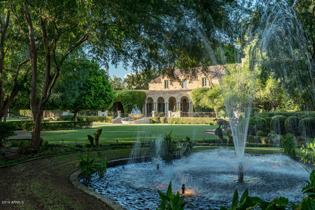 Elegant Santa Barbara architecture makes for a stunning silhouette against two and a half acres of lush landscaping.  Fountains, secluded patios, and ramadas as well as a separate guesthouse and a pool house, create interest throughout the fully walled and gated property.  Inside you will find lovely solid hardwood flooring and custom cabinetry.  4 en-suite bedrooms in main house; the master retreat and office upstairs, is accessible via the spiral staircase or by elevator.   2-bedroom guest house is currently being used as an office; included are an efficiency kitchen and fireplace.  Pool house is set-up to also be used as a catering kitchen for large scale entertaining. This home offers the secluded feeling of a country home with a location just minutes from Scottsdale and Sky Harbor.