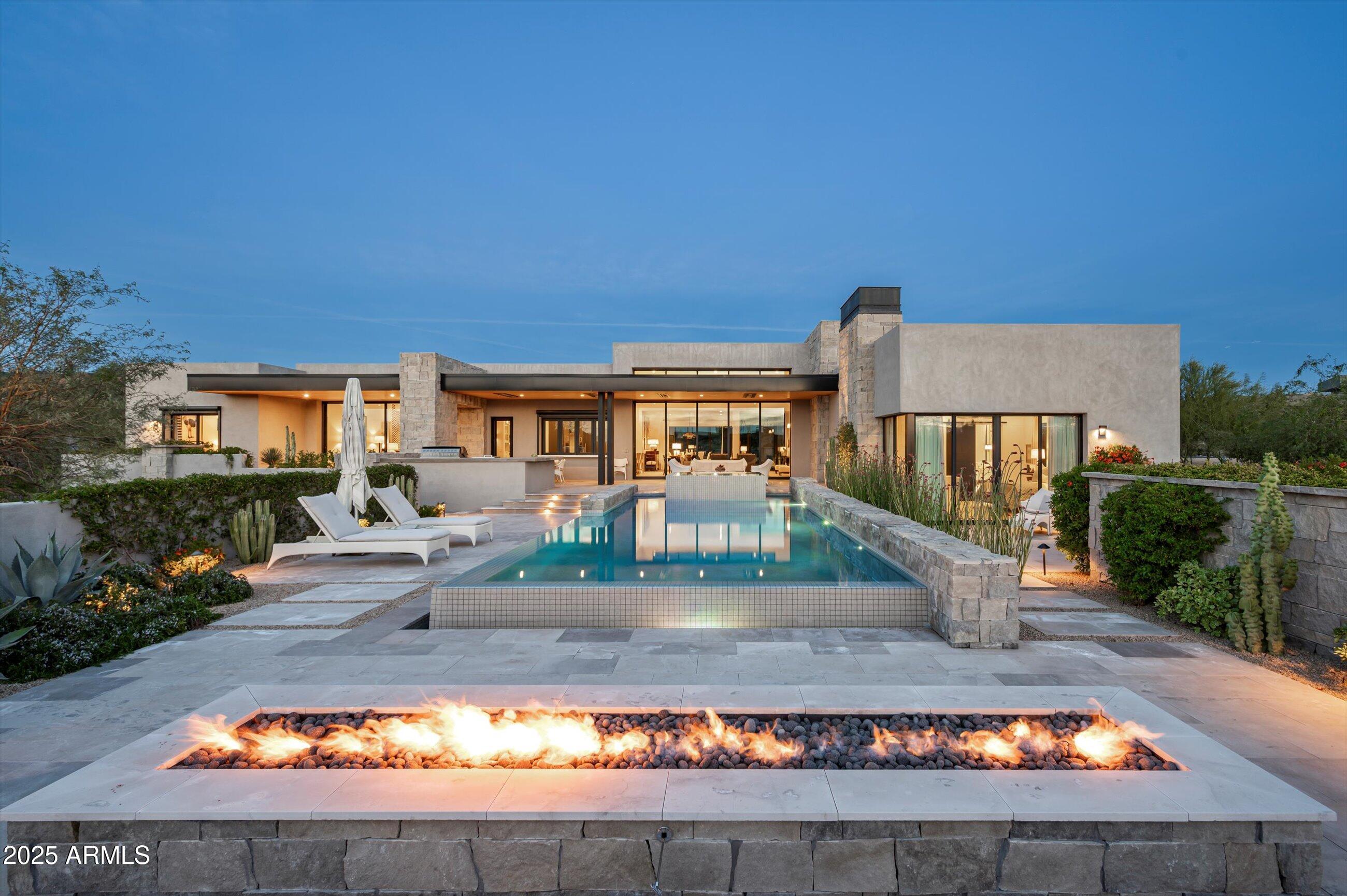 Live the Desert Mountain lifestyle at its finest in this 2023 custom-built modern estate—meticulously crafted, highly upgraded by the sellers during and after construction, and designed to feel as stunning as it is livable. FULL Golf Membership available. With 4 bedrooms plus a secluded office, 4.5 baths, split floor plan, 3 car insulated garage, every space is intentional—warm, sophisticated, and built for effortless hosting.
At the heart of the home, the kitchen is a true showpiece with oversized Sub-Zero, Wolf, and Cove appliances and a generous walk-through butler's pantry complete with sink and another Cove dishwasher—perfect for catering, entertaining, or simply keeping everything beautifully organized.
Movie nights become an experience in the media room, where, a refined wet bar includes two oversized wine refrigerators, an ice maker, sink, bar seating, and open shelving to showcase your barware. The indoor outdoor experience is heighten with the pocket  glass panel wall that blends the family room and kitchen into the outdoor living space for the ultimate Arizona indoor-outdoor flow.
Under a tongue-and-groove wood ceiling with built-in heaters, the patio becomes a year-round destination. A pass-through bar connects seamlessly to the kitchen, enhanced with two refrigerated beverage drawers for poolside refreshments. Step outside to an elevated spa spilling into the heated pool, set against a dramatic fire feature and wide-open viewswhere colorful sunsets steal the show night after night.