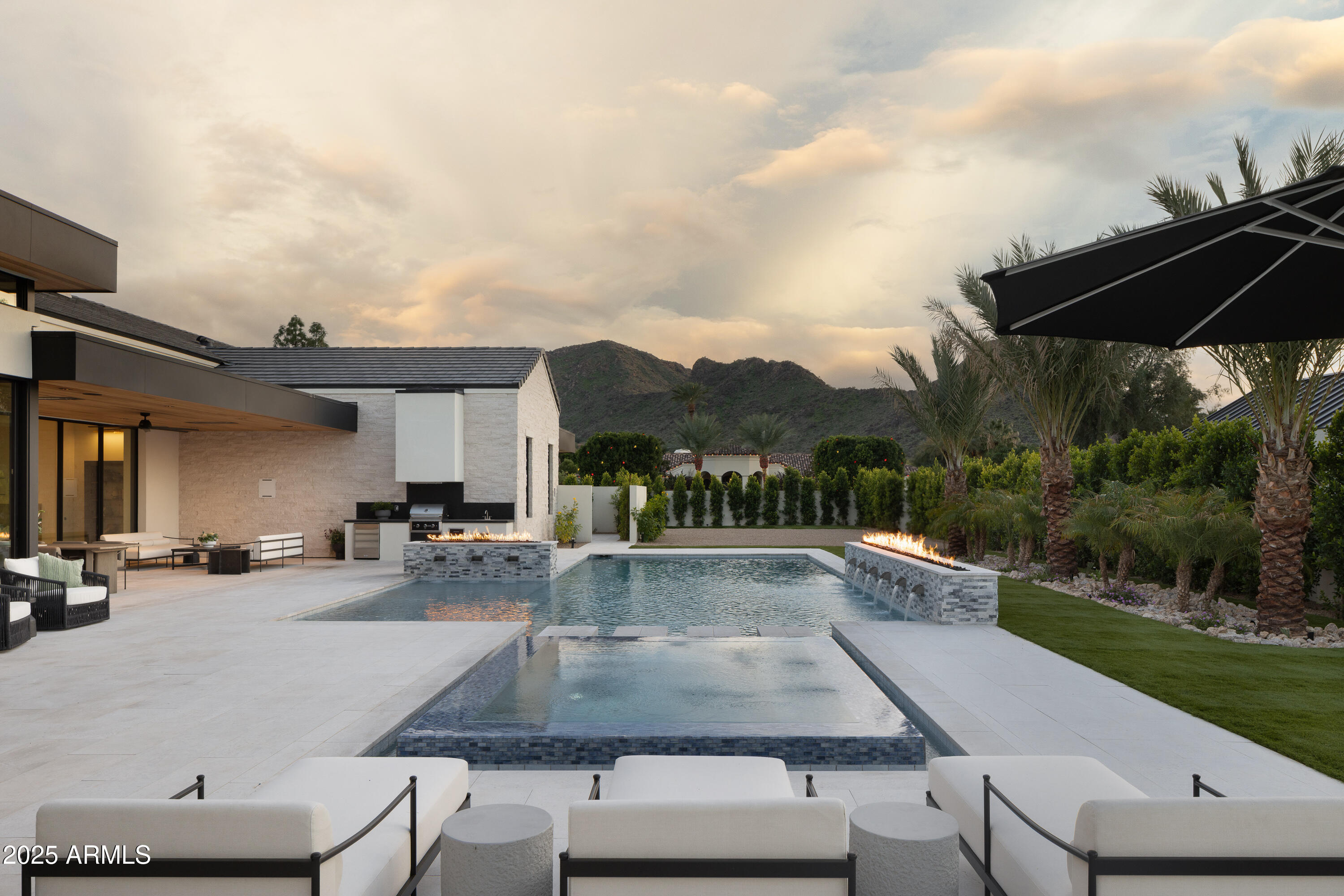 Located on one of the most prestigious streets in Paradise Valley, experience exquisite luxury and designer elegance in this brand new custom residence crafted by Patterson Homes and London Pierce Design. Every detail has been thoughtfully curated with sophisticated finishes throughout the home. The chef's kitchen showcases a 60'' Wolf range, Sub-Zero fridge/freezer, and beautiful butler's pantry with ample storage. Entertain effortlessly in the expansive game room fully wrapped in rift oak, complete with a walk-in wine cellar and stunning mountain views overlooking the private spa. The inviting primary suite captures incredible mountain views and features a gas fireplace wrapped in custom marble, spa-like master bathroom with dual vanities and water closets, large his and hers closets, complete with a separate full laundry room. The beautiful home office overlooking the front landscaping, full workout room with mountain views, gameroom, and three generously sized ensuite bedrooms all in the main house. A detached casita provides additional living space with its own living room and ensuite bedroom. Resort-style amenities include a temperature-controlled four-car garage, large pool with an additional spa, pickleball court, and Control4 automation throughout. This exceptional estate offers the ultimate in luxury living in Paradise Valley's most sought-after location.