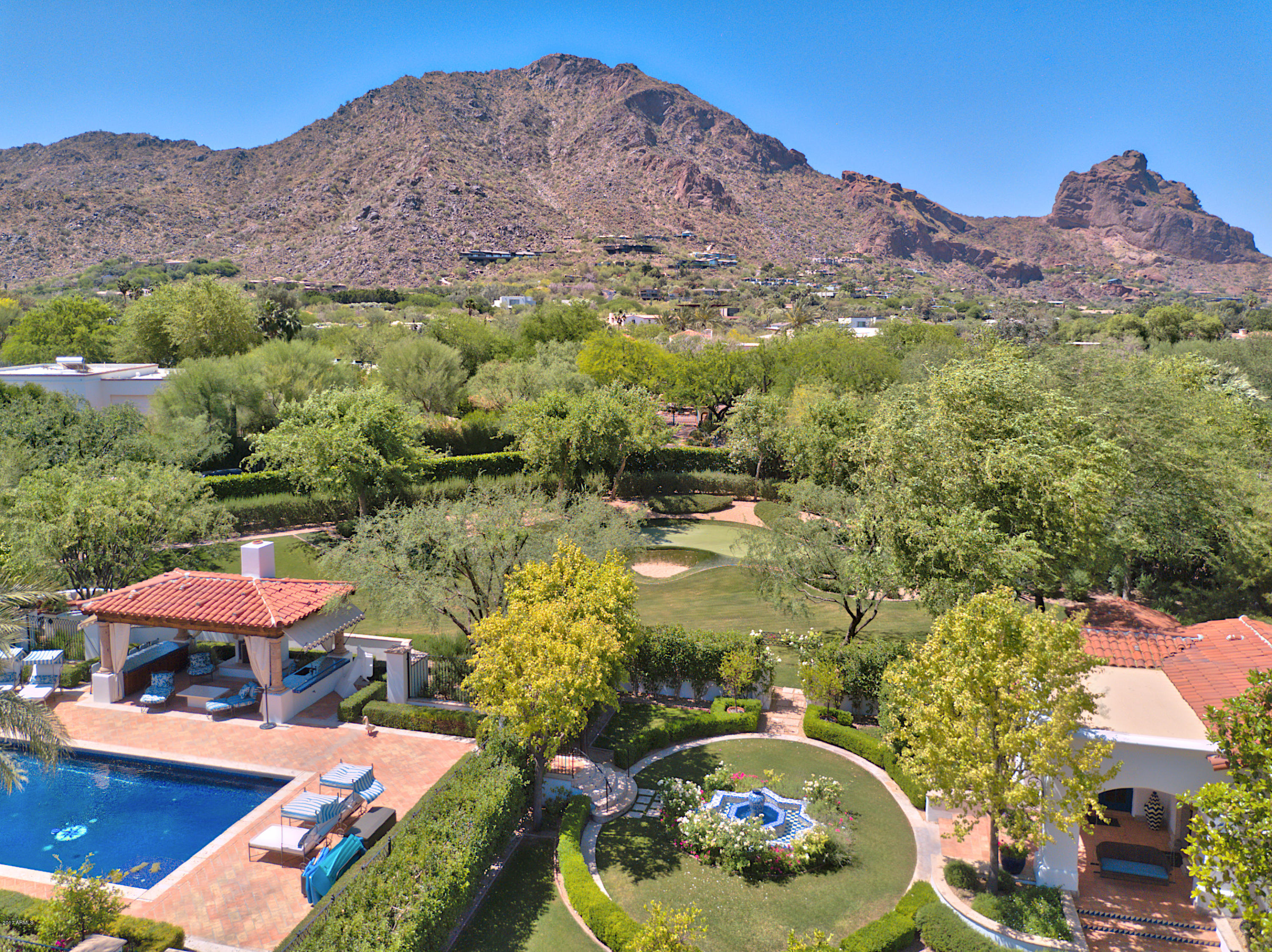 From the moment you pass thru the private gated entry of this 2.23 acre estate with hand-painted directional tiles, you will be captured by it's charm and the stunning Camelback Mountain views. It boasts 12,295 sq.ft.,16 ft ceilings, a phenomenal backyard and an attention to detail that will excite the most discerning buyer!!
 Multiple French doors frame Camelback Mtn and open to the expansive lawns, a fully tiled pool, cabana, sport court, putting green + play area. Stroll along a private jogging path + flower gardens and feel a sense of serenity. Highlights include a 2 bdrm guest house, separate exercise bldg. (or 2nd guest house)  2 family rms an elegant 2 story high walnut library, white designer Chef's kitchen, white carrara marble bathrooms + 2 huge outdoor entertainment patios. Features include hickory flooring, specially hand crafted commissioned cabinetry, hand-forged ironwork + iron-strapped trestle-beam and groin vaulted ceilings.
The magnificent craftsmanship, exquisite finishes, and inviting appeal make this one of the finest estates in Paradise Valley.