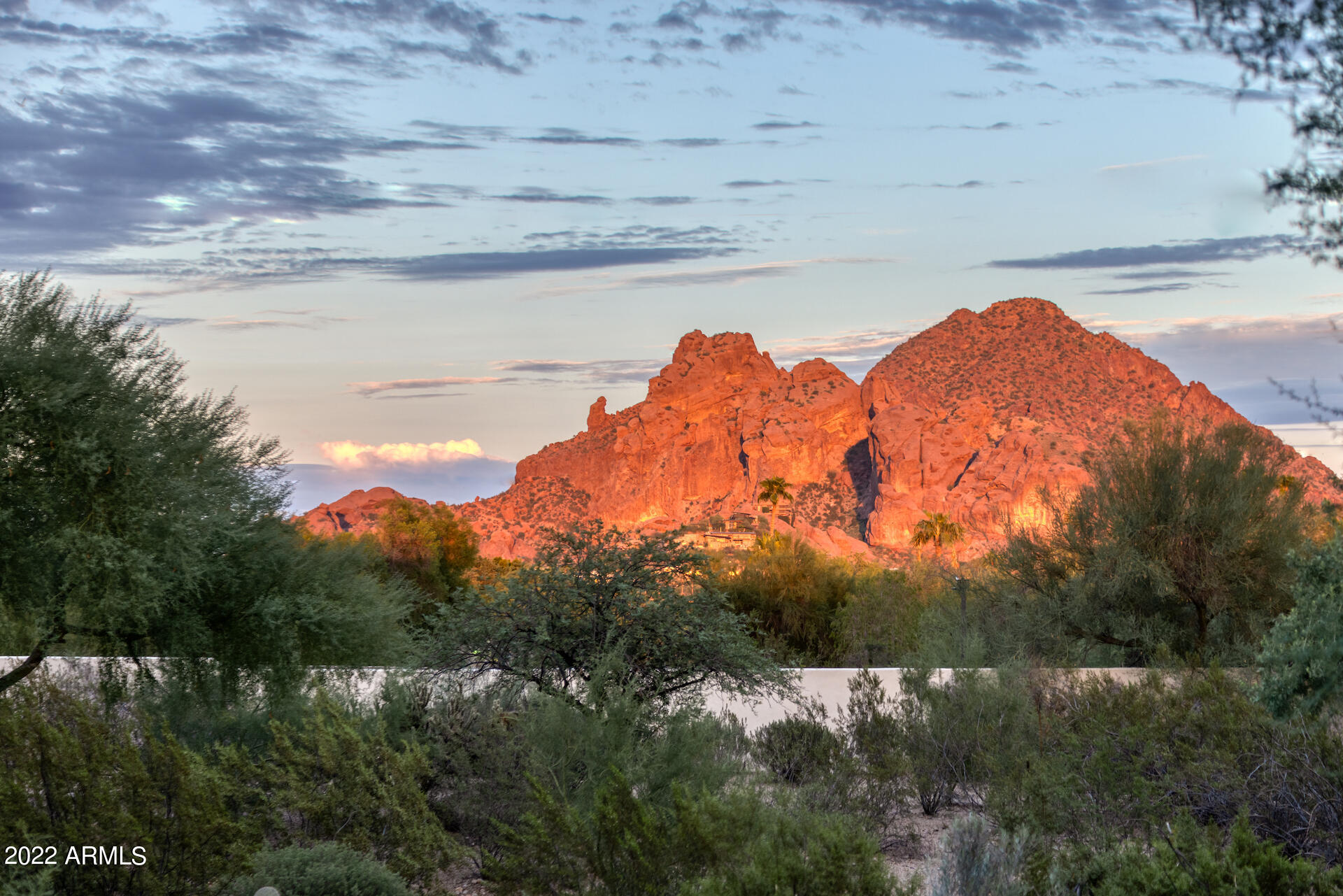 This privately gated desert estate on over 2.45 acres located in the sweet spot of Paradise Valley and possessing sweeping views of Camelback Mountain and the Praying Monk, was beautifully remodeled in 2021 with a light and contemporary color scheme of crisp whites and pale grays.  Totally remodeled kitchen including chef's quality appliances, custom cabinetry, quartz countertops, custom lighting and a coffee bar.  There are three remodeled secondary bedrooms with en-suite bathrooms. each one different in design; each includes high end custom tile work, marble and finest plumbing fittings. Gorgeous wide plank wood floors throughout compliment the previously added game room addition and gorgeous primary suite remodel. A fully self-contained guest casita includes a  separate kitchen, bathroom, bedroom, and sitting room.  Even the windows and interior doors were replaced.  Originally designed by Arizona legend, George Christensen, the timeless Santa Barbara architecture will never age.  Creamy white walls and classic red tiled roof are offset by a meticulously curated indigenous landscape. The exterior boasts multiple covered patios, a built-in bbq and fireplace, a large pool and heated spa, and plenty of space to add a grassy play yard or tennis court.  With four garages, this is a home not to be missed.  Walking distance to Phoenix Country Day School, The Biltmore Resort, great restaurants, and coffee.
