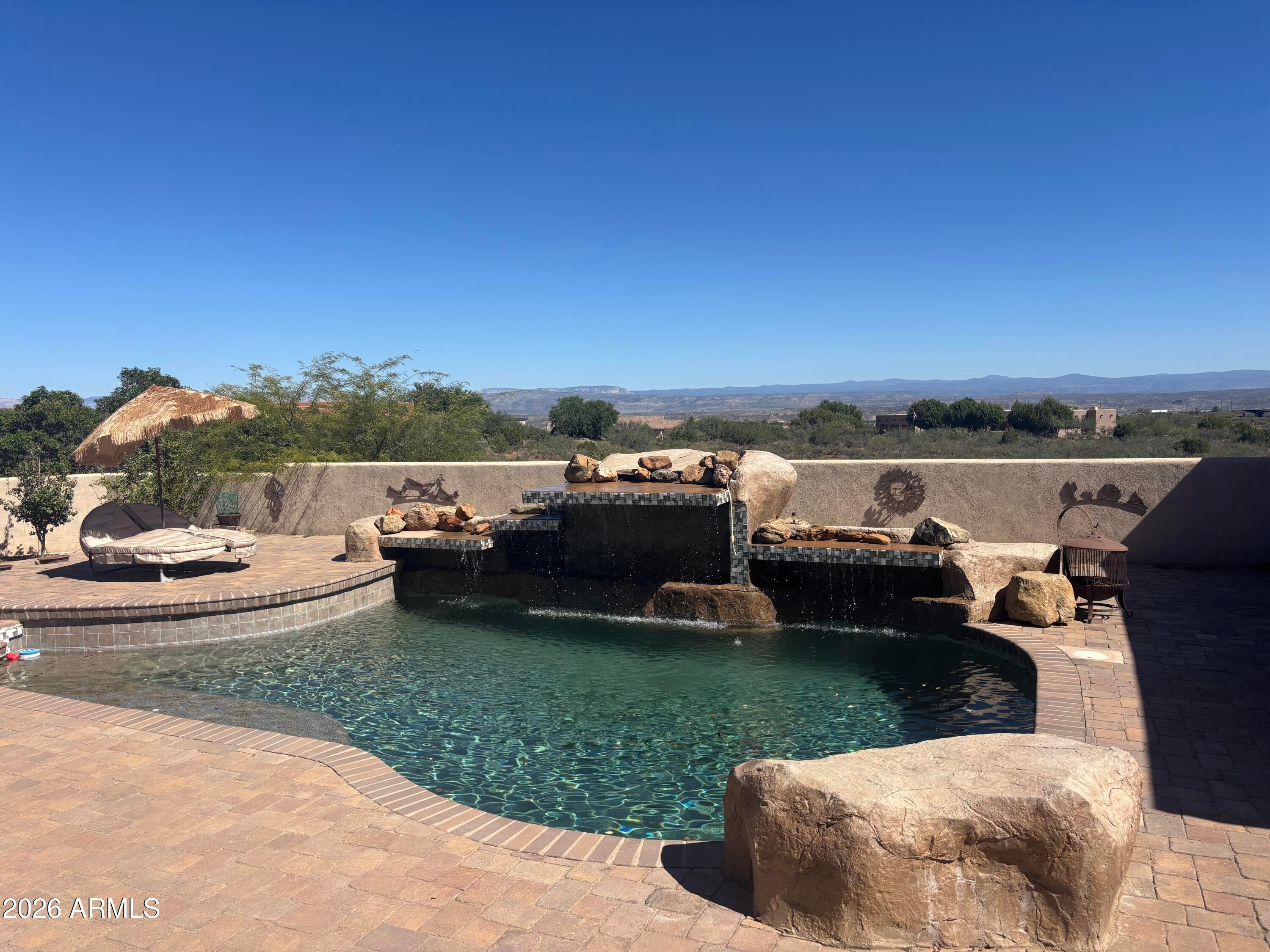 Sedona-view equestrian estate without Sedona prices, taxes or traffic.  No congestion here! 4.97 private acres of your very own sits at the end of a cul-de-sac, bordering National Forest, with panoramic Sedona Red Rock and Mingus Mountain scenery. The 4BR, 4 bath home features a custom granite chef's kitchen with statement chandelier, formal dining room, and a 450-bottle wine room. 3 bedrooms offer flexible use as an office or guest space, and a dedicated pool bath adds convenience for outdoor living.
The primary suite includes a fireplace, spa-style bath, and direct walk-out access to the pool. Geothermal heated flooring provides year-round comfort.Outdoor amenities include a pool, outdoor shower, RV parking, well, solar system, circular drive, and full privacy wall.  Bring me your offer
