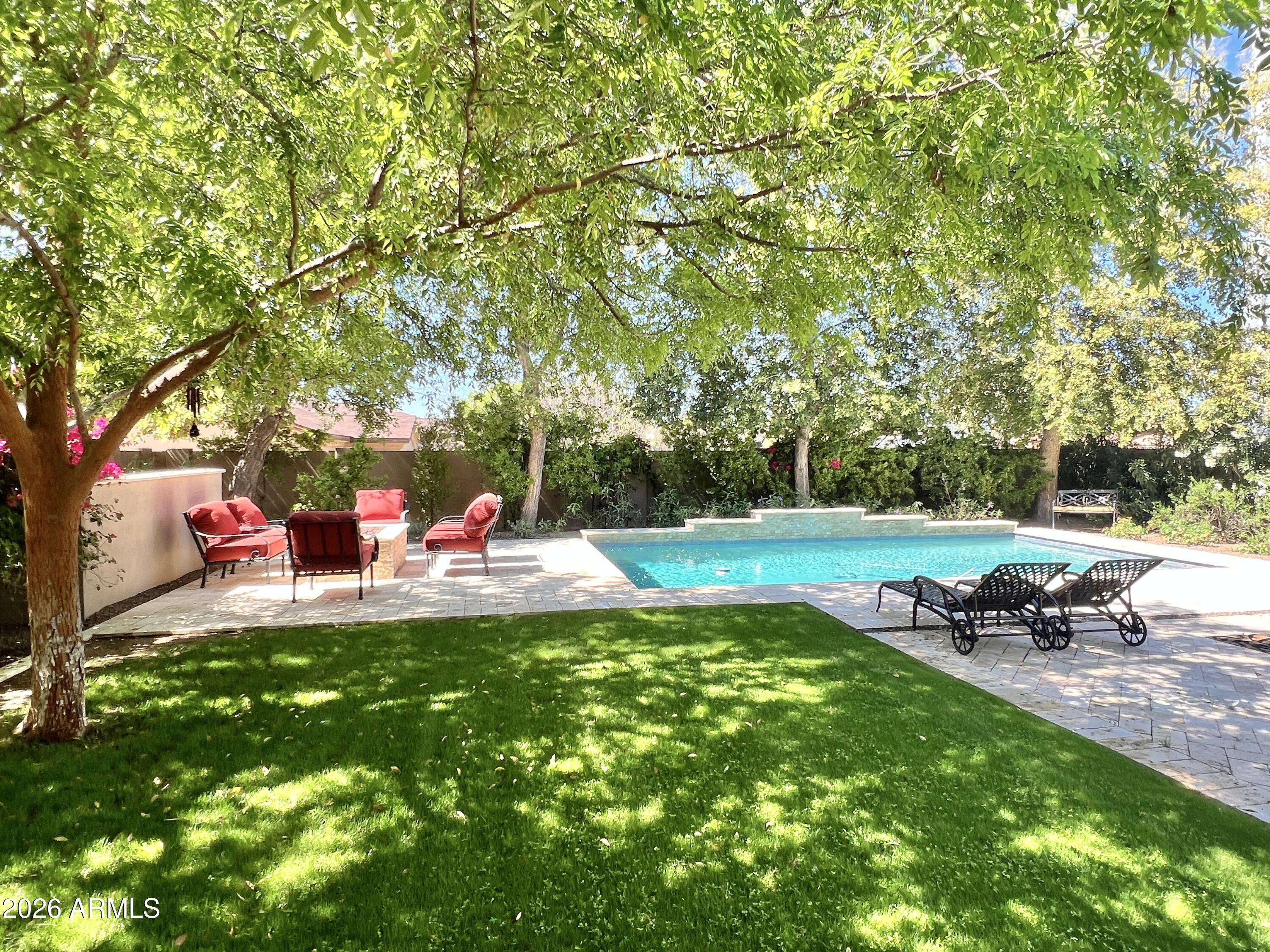 4632 SQFT 5 bed, 4 bath gated home with 3 car garage, heated pool on a 10,130 SQFT lot in Lower Arcadia Lite. This home offers a combination of size and amenities that is increasingly difficult to find at this price point in Lower Arcadia Lite without compromise. Tucked inside a private gated court of just eight homes, the setting immediately feels charming, secure and private. Step inside and the home opens up with the bright white kitchen, family room, living room and dining room flowing together into one expansive, connected space designed for real life and entertaining. A walls of glass slides open and creates the perfect indoor/outdoor living. Heated pool finished in Aqua Blue Luminous PebbleSheen with Abalone Shell blend, three sheer waterfalls, gas fire pit with cocktail ledge, BBQ built in, covered patio with outdoor TV, real grass, and mature trees that create a setting that feels both elevated and easy to live in. The home layout hits what buyers are actually looking for; FIVE large bedrooms, a dedicated office, 322 SQFT loft, and four full baths including a main level guest suite that works for guests, extended stays, or a second workspace. Upstairs, the loft with ceiling speakers and 75 inch TV flexes easily as a media room, gym, or play space. Every bedroom includes a walk in closet, with dual closets anchoring the primary suite. Construction and upgrades bring the quality forward. 9 foot ceilings, 8 foot paneled doors, cabinetry to the ceiling, spray foam insulation, engineered hardwood floors, designer LED lighting, Hunter Douglas power shades, Avalon 150 bottle wine refrigerator, beverage refrigerator, and full size Frigidaire Professional side by side refrigerator and freezer. Recent updates include new water softener, hot water heater, and dishwasher. The home has been consistently maintained with a home warranty in place since 2019, with roof inspection and HVAC servicing completed just prior to listing. Three car garage configured as 2 plus 1, walk in pantry, under stair storage, RV gate, Samsung washer and dryer, and all televisions included. Freshly painted and ready to go. Minutes to the Biltmore, Fashion Square, and Old Town Scottsdale, with access to highly regarded schools including Brophy College Preparatory, Xavier College Preparatory, Phoenix Country Day School, and Villa Montessori School. UBER to Sky Harbor from your gated neighborhood within 10 minutes makes this the PERFECT location.