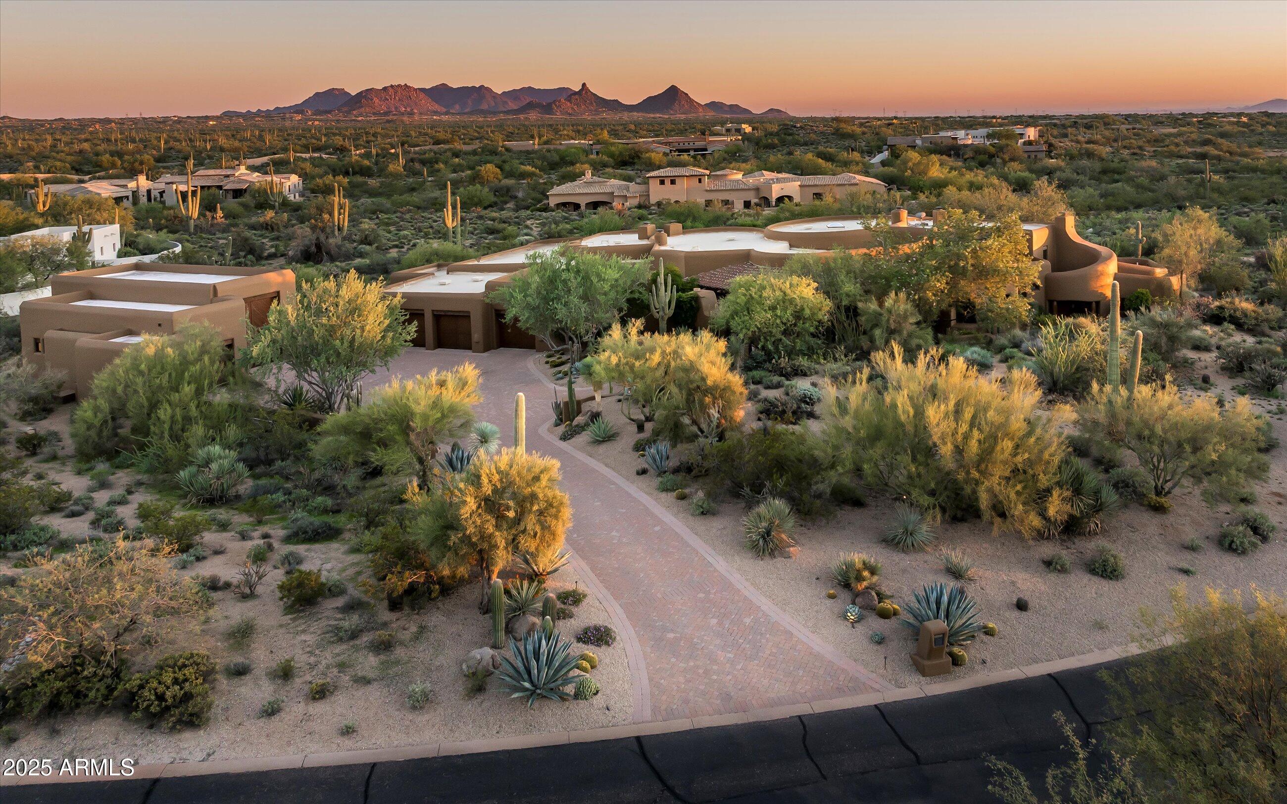 Authentic Pueblo-style estate designed by renowned architect Lee Hutchison and built by award-winning RS Homes. Set on nearly 3 acres within the private, guard-gated community of Whisper Rock Estates, this home showcases timeless craftsmanship and rich finishes throughout. The open floor plan features a chef's kitchen with adjoining hearth room, formal dining with wine cellar, spacious great room, master retreat, elevated office with view deck, and a junior suite. A rare, climate-controlled garage for 10+ cars caters to the discerning collector. The fully self-contained guest house offers a kitchenette, living room with fireplace, two bedroom suites, and laundry. Exquisite details include viga beams, reclaimed wood floors, exotic stone, and full home automation. Outdoor living is unmatched, with multiple fireplaces and fire pits, a ramada for entertaining, heated pool and spa, covered media area, and several private patios.