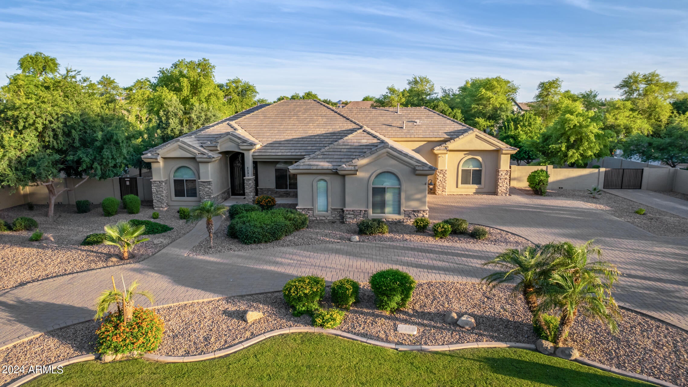 The perfect blend of elegance and comfort in the most coveted neighborhood! Perfectly situated on a corner lot with a circular driveway and mountain views. Enter through the iron front double glass doors into a grand foyer, leading you effortlessly to the formal dining room, private office with custom built-in desk/murphy bed and living room with high tray ceilings and elegant travertine flooring.  The heart of the home is the gourmet kitchen with high-end appliances, granite countertops, custom cherry cabinets, pull out shelves, gas cooktop and large island with seating that opens to the Breakfast Area and Family Room with Gas Fireplace. A spacious master suite features a walk-in closet, double vanity, soaking tub, walk-in shower and double door exit to the back patio. Plus, three additional bedrooms with walk-in closets and an option to convert the den into a fifth bedroom. Your backyard desert oasis awaits...the perfect blend of water and fire with an ocean blue pebble sheen play pool, complete with heated spa, outdoor kitchen, separate fire pit seating area for cozy gatherings, shoot hoops on the half basketball court or enjoy the ramada and playground. Take advantage of the 40-foot by 15-foot slab parking behind the RV gate. This outdoor space has it all. Come Discover Your Dream Oasis!!