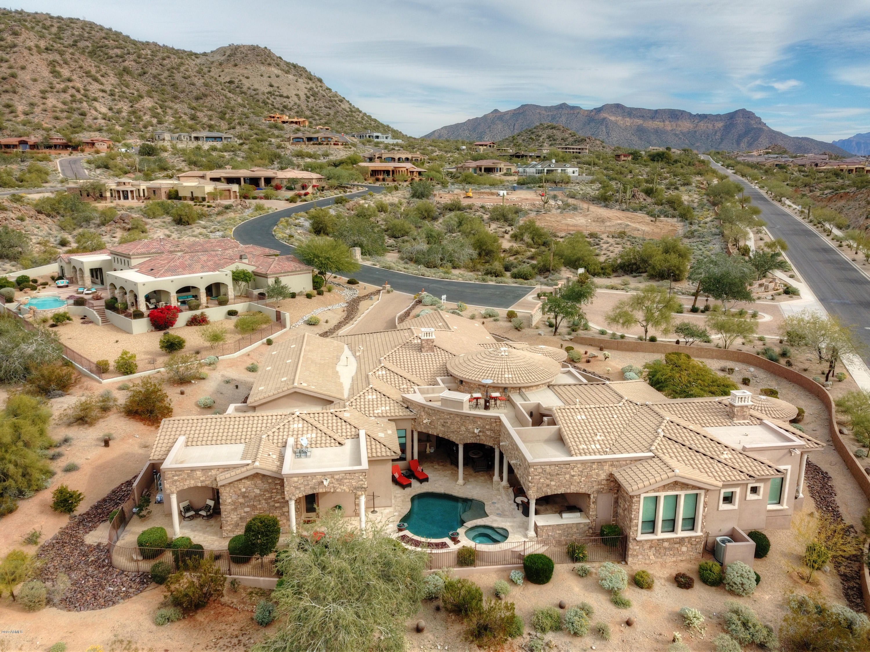 PRICED WELL BELOW THE COMPS FOR QUICK SELL! Extraordinary wrought iron entry door leads you to a ''breathtaking'' entry/foyer complimented with serene desert sunset views through the floor to ceiling windows! Separate open living & dining rooms & 5BR, 5.5BA. Addt'l rooms include an exercise/game room, a theatre w/ surround sound  & a custom service bar. Intricate travertine & wood floors, carved wood beams, natural stone, fireplaces, stunning lighting accents & smart home capable throughout! The kitchen is a culinary dream feat. custom hand-carved cabinetry, huge walk-in climate controlled wine cellar, top of the line VIKING cooktop-dual ovens, (2) service islands with GRANITE counters, built-in SubZero fridge & separate pantry. Oversized 4-Car gar. + 44'8'' RV gar. w/14ft. overhead door. Beautiful split plan with a HUGE master bedroom that features a private balcony, 2-way fireplace and a stunning walk-in closet with custom organizers and designers carpet. 
Sizable bedrooms 2 through 5 feature their own bathroom and walk-in closets. Home also features 2 tankless hot water systems with recirculating hot water and an owned water softener in addition to an RO system at the kitchen sink. 
Surround sound allow each room to have a volume control, working from one of the controls located in kitchen, great room, game room, patio door or master bedroom. Ambient low-level lighting creates a peaceful atmosphere no matter the time of day!
The backyard has a way of making you feel like you're on vacation with the heated pool & spa, custom fire pits, misting systems, separate elevated BBQ area, massive patio. The roof top VIEW DECK with custom seating and a fireplace to add to the ambiance and comfort is what makes you say "LIFE IS GOOD".
Turn-key and ready to go, absolutely no updating necessary with this home!
Superior location, only 30 minutes east of Phoenix, 15 minutes north of Mesa Gateway airport.  Not to mention that you can now launch your boat in minutes, as you are now located only 25 minutes from both Saguaro and Canyon Lakes!