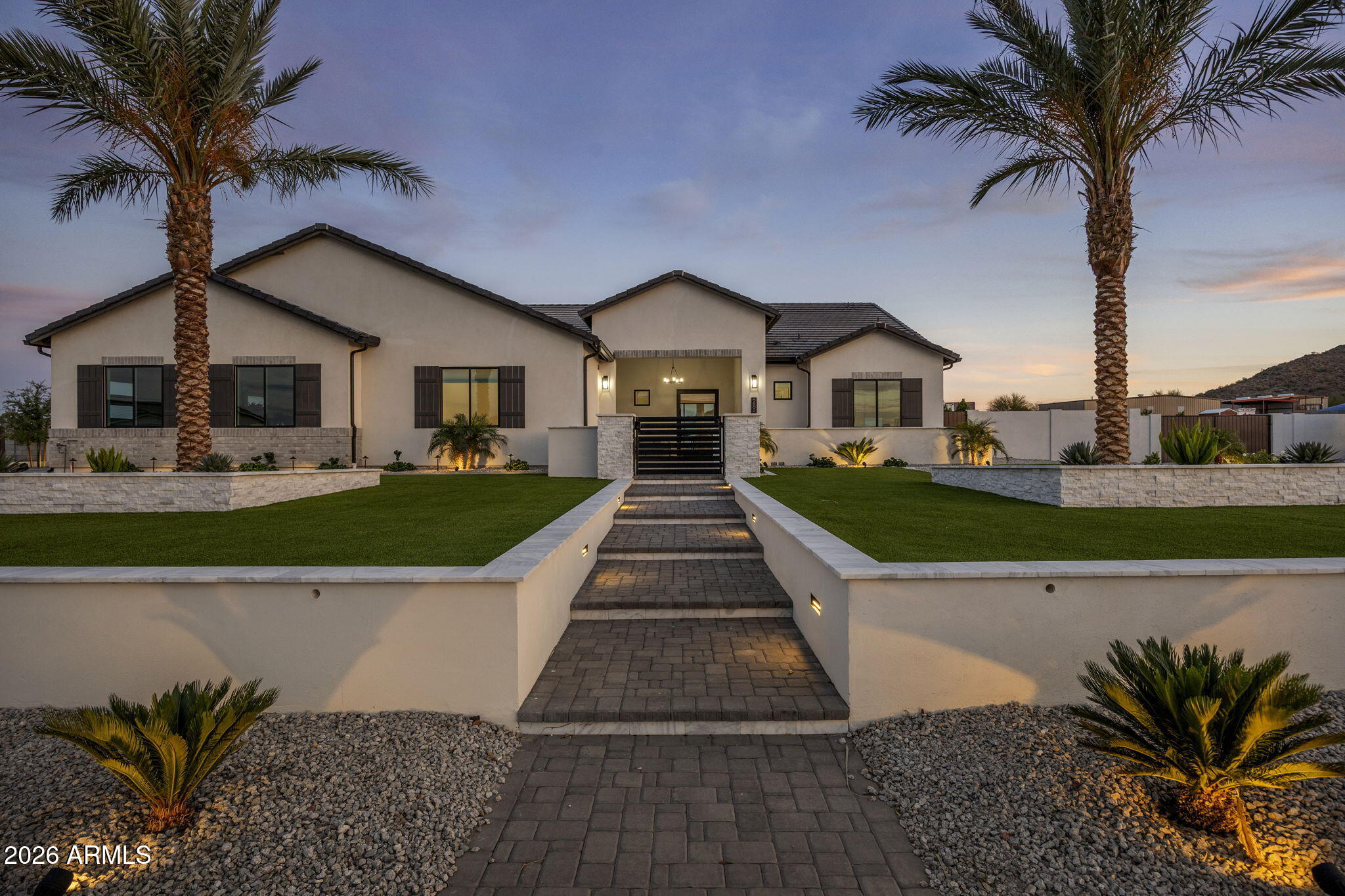 Why wait to build when you can own better than new? Built in 2024 and immediately elevated with over $500,000 in premium upgrades, this exceptional Queen Creek estate delivers luxury, functionality, and resort-style living on a sprawling 1.25-acre lot with NO HOA.
Offering 3,080 sq ft of thoughtfully designed living space including an attached casita with interior and exterior entrance --perfect as a mother-in-law suite or guest retreat--complete with its own full wet bar, custom cabinetry, lighted floating shelves, and a striking herringbone tile backsplash.
Step through the impressive custom 8-foot glass pivot front door into a home filled with high-end finishes and modern elegance. A dramatic 20-foot pocket sliding wall of glass seamlessly blends indoor and outdoor living, (MORE) while the Roman Clay fireplace media wall--accented by under-cabinet lighting, floating shelves, and custom built-ins--creates a warm, sophisticated focal point.
The gourmet kitchen features quartz countertops, stainless steel appliances, double ovens with convection, a 36" induction cooktop, and designer lighting throughout. Wood-look plank tile flows seamlessly across the entire home, complemented by custom touches like shiplap feature walls and a fully built-out primary closet system.
Retreat to the spa-inspired primary suite, complete with a freestanding soaking tub, oversized walk-in shower with rain head, and beautifully custom-tiled bathrooms throughout the home.
Outside, the property transforms into a private resort. Enjoy a heated pool and spa, lush turf, towering palm trees, ficus privacy hedges, a putting green, raised garden beds, and full landscape lighting with irrigation throughout. Entertain effortlessly with a fully equipped outdoor kitchen under a ramada, fire pit, overhead heaters, and misting systems for year-round comfort.
The entire property is enclosed with stucco block walls, and features an inground propane tank, gutters, and expanded concrete driveway with extended apron. The cozy front courtyard with pavers and custom gates adds charm, while double RV gates on both sides provide full pull-through access and ample space for toys, equipment, or a future shop/RV garage.
Car enthusiasts will appreciate the oversized 4-car garage with upgraded insulated doors and ceiling. Additional features include a water softener system and a fully integrated SONOS audio system throughout the home, patio, and ramada.
Set on a quiet, boutique dead-end street surrounded by new homes, this property offers stunning 360-degree mountain views and the perfect balance of peaceful country living just minutes from town.
This is a rare opportunity to own a truly turn-key, designer-upgraded estate with every detail already complete--schedule your private showing today and experience the lifestyle this one-of-a-kind property has to offer.