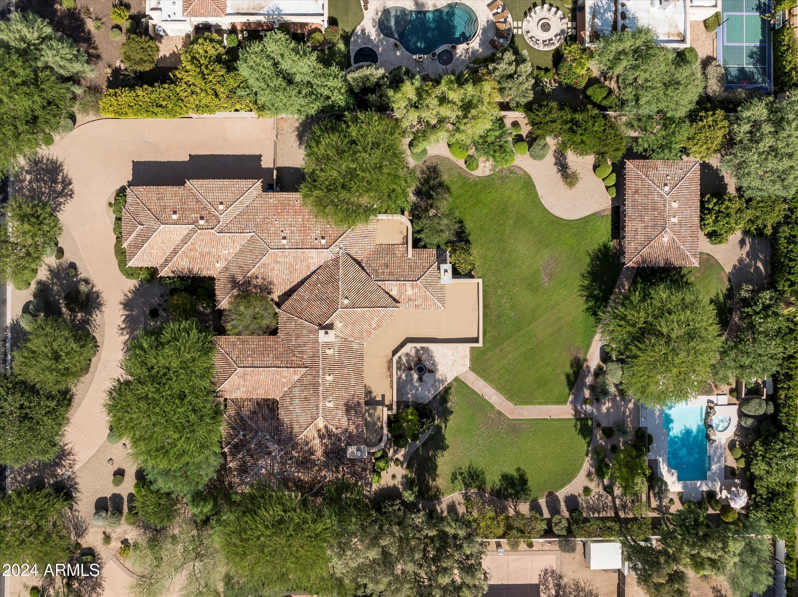 Located Paradise Valley's prestigious 85253, this extraordinary estate sits on a rare 50,471 sq. ft. lot, offering unparalleled privacy, breathtaking Mummy Mountain views.
A grand circular driveway and impressive wrought iron French doors set the tone for this timeless residence, welcoming you into a home designed for both grandeur and comfort. The 6,299 square foot main home is thoughtfully designed, and incudes a 500 square foot guest house—perfect for visitors or extended stays.
Upon entering, you're greeted by a warm family room and an elegant formal dining space, each showcasing stunning mountain vistas. A climate-controlled 216-bottle wine room seamlessly connects the dining area to the stylish bar, making this home perfect for entertaining. The gourmet kitchen, overlooking the spacious living room, features a wall of windows that frame the expansive backyard, creating a seamless indoor-outdoor experience. Three spacious en-suite bedrooms are thoughtfully positioned near the kitchen, offering comfort and convenience for family or guests.
The master suite, situated separately from the secondary bedrooms for ultimate privacy, is a sanctuary of relaxation. This expansive retreat boasts a sitting area, coffee bar, spa-inspired bath with his-and-her vanities, an oversized shower, walk-in closet, and a private sauna. Across from the master suite, a large home office with an en-suite bath provides a quiet and functional workspace.
Designed for the ultimate Arizona lifestyle, this estate features an oversized covered patio, perfect for entertaining, with a built-in barbecue, landscape lighting, and elegant pillar uplighting. The expansive pool and spa, set against a stunning mountain backdrop, create a serene oasis for warm summer days.
Beyond its beauty, the sprawling backyard offers endless possibilitiesplenty of space for kids to run and play freely or to add a pickleball court, basketball court, or other recreational amenities.
The private guest house is a retreat of its own, complete with a spacious bedroom, full kitchen, bathroom, and its own covered patio, offering both independence and comfort for guests or extended stays.
This rare offering combines luxury, privacy, and breathtaking views in one of Paradise Valley's most sought-after locations.