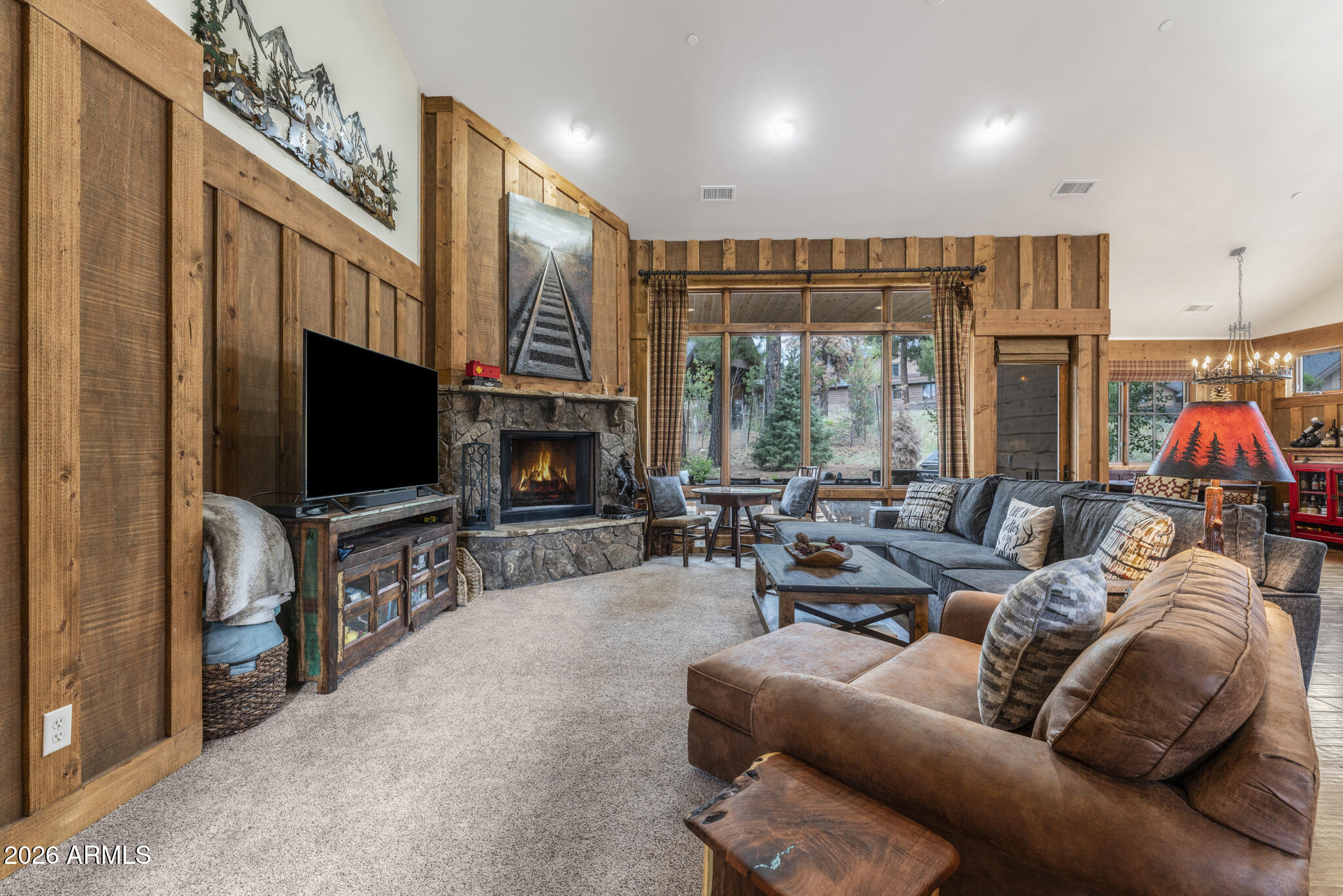 Nestled within the sought-after Deer Creek neighborhood, this charming cabin is ideally positioned on a quiet cul-de-sac lot, offering convenient access to the Clubhouse and Pine Canyon's premier amenities. Thoughtfully designed for both comfort and mountain living, the main level welcomes you with expansive windows that fill the great room with natural light, while a stunning Flagstaff-native stone fireplace creates a warm focal point for gathering and relaxing. Rich wood flooring throughout the main level, paired with natural wood siding accents in the great room and primary suite, enhances the home's inviting mountain-lodge feel. The kitchen is well-appointed with granite countertops, stainless steel appliances, and a spacious island with bar seating, perfect for entertaining or casual dining.
The home features three private en-suite bedrooms, each with dual vanities, including two conveniently located on the main level and an additional guest suite upstairs. The primary suite offers a peaceful retreat with direct access to the patio, complete with a built-in BBQ--ideal for enjoying cool mountain evenings and seamless indoor-outdoor living.
