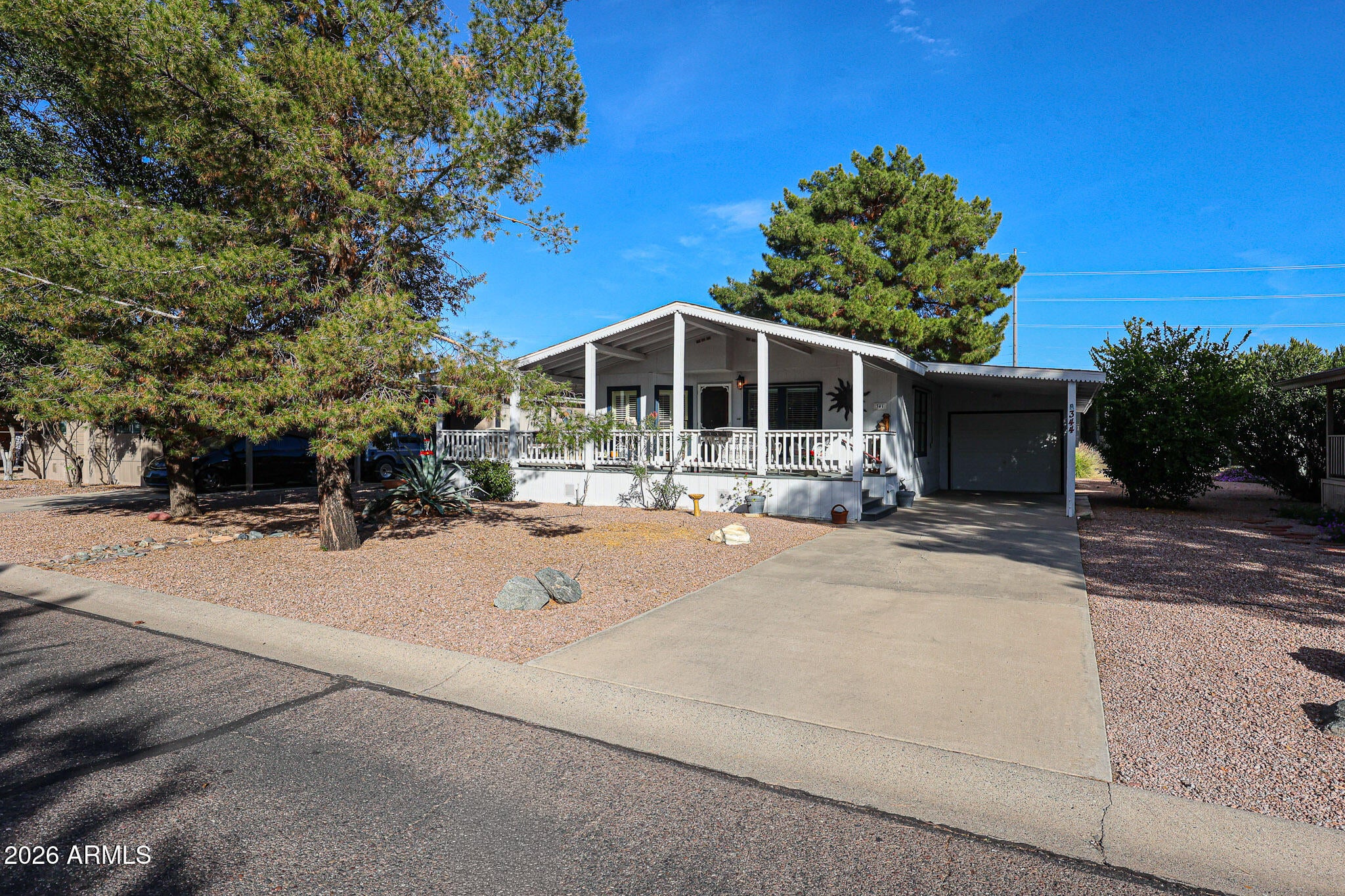 So much character on this large wrap around front deck!  Curb appeal +.  GARAGE Plus large workshop attached to home.  Rare find.  HVAC 2025.  You must see this cozy home with 2 bedrooms plus an enclosed Arizona room plus the 9ft wide front covered deck.  Plenty of room.  Murphy bed in 2nd bedroom.  Hard floors throughout.  W/D stay with home and extra fridge in garage stays. Well maintained.  This 55+ community is also a gem!  Located in the Desert Ridge area with a 9 hole executive golf course and heated pool  The 24/7 manned guard gate provides peace of mind!  Monthly land lease $970/month.  The clubhouse has a remodeled pool, hot tub, game room and lots of social activities.  Be active or just stay home in this quiet gated community.   No rentals allowed. 30lb dog limit. Great Location