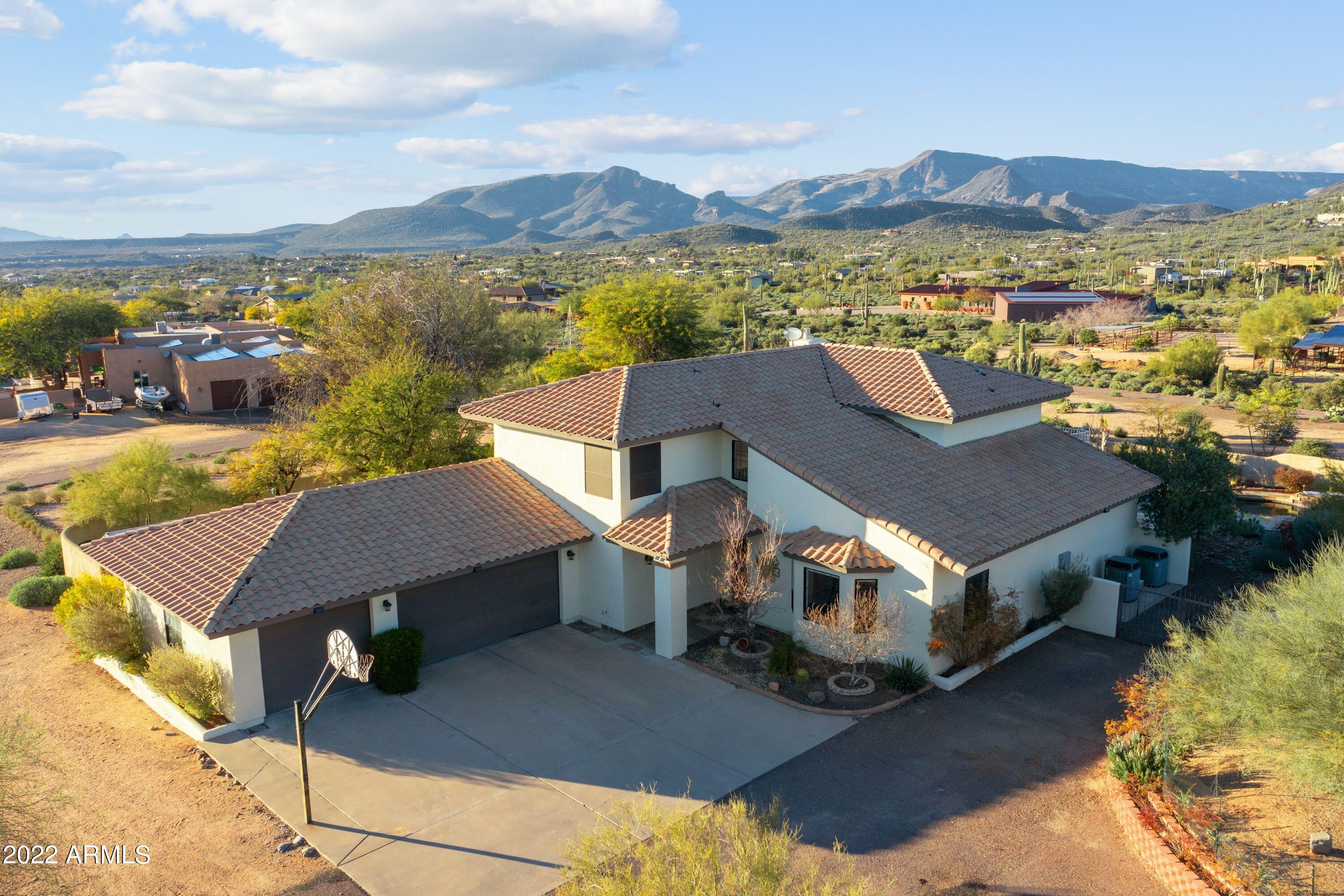 This home/property boasts real Million Dollar views.  Sit out by the Pool or up on the 2nd floor deck and check out the 360* views of the Cave Creek Mountains.  The home has been continuously upgraded from 2007 and is a rare two-story home located on the million-dollar mile, north of beautiful Cave Creek.  This incredible property is sitting on over 2 acres and has gorgeous landscaping and has been well cared for. The house features an oversize 3-car garage, walk-in pantry, large main floor bedroom with a walk out sliding door to the back garden. The 2nd floor consists of a large master bedroom/bathroom with a walk-in closet, two guest rooms with a Jack and Jill bath and ample closet space.  The upstairs was remodeled in 2014 and new carpet added in 2022.   See Supplement for more. The kitchen boasts of a large island with a built-in induction glass top stove and top of the line Thermador appliances. The kitchen and living area were remodeled in 2007, then again in 2013 with new Travertine tile. 
All counter-tops throughout the house are granite. There is a two-person office with built-in file cabinet sized drawers (Could be a 5th Bedroom). Included is a separate pantry/storage closet for those seldom used cooking items. You will not be disappointed with the main level storage! 
The diving pool is propane heated and the pool area was completely remodeled with flagstone, pebble tech and tile in 2008. The oasis back yard is a burst of color surrounding synthetic grass. The pavers are awaiting your fire pit and lounge furniture! Propane lines are buried to the pool heater, three fireplace/fire stands and the interior linear remote-controlled fireplace. This property has a private well and septic. If you enjoy stunning sunsets, mountain views and privacy, you must see this property!
