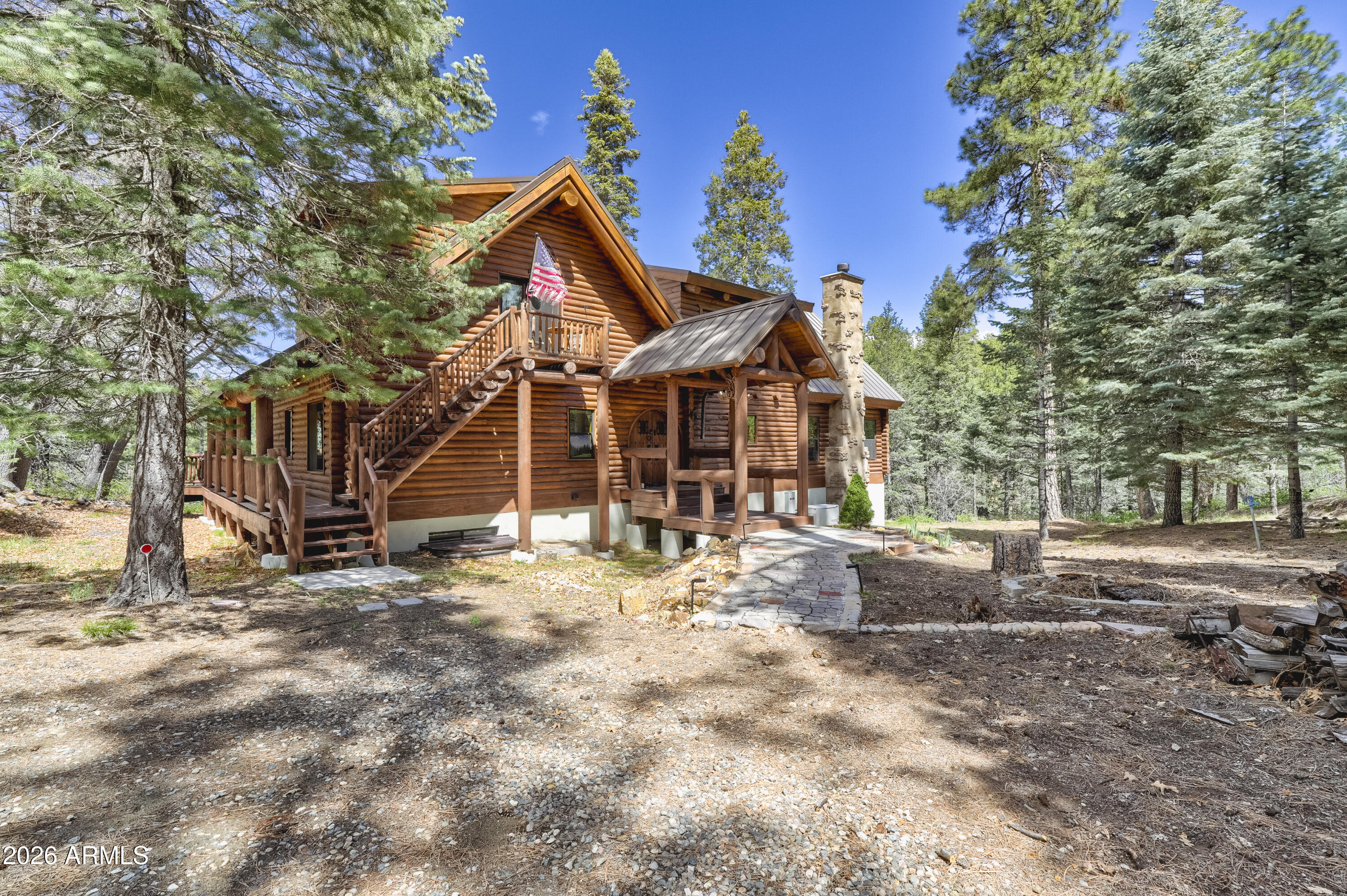 This gorgeous custom built log home with beautiful Douglas fir beams on over two acres situated at 7,000 ft altitude is nestled in the majestic cool ponderosa pines backing to the National Forest. You can live on one level or enjoy the beautiful large primary bedroom on the upper level which has an electric fireplace, sitting area, primary full bath with large soaking tub, seperate shower, large closet area and workout area with views. The main level has a bedroom, living room with fireplace,family room with fireplace, bathroom with a hammered copper clawfoot tub and shower, eat in kitchen. Enjoy the cool summers on the large open & covered deck with view of the seasonal creek and plenty of room for the whole family and friends. Downstairs there are four bedrooms, two 3/4 baths one being a Downstairs there are four bedrooms, two 3/4 baths one being a Jacuzzi shower. For your guests there is a coffee bar room with a standard size refrigerator, sink, microwave, toaster oven and a  unique, custom wood counter top made from trees on the property. Step outside from the lower level and enjoy the patio with a newer hot tub and view of the seasonal creek. Be sure to look at the document tab to see all the upgrades the current builder/owner had done to the property in the last two years. This could be a turnkey opportunity.