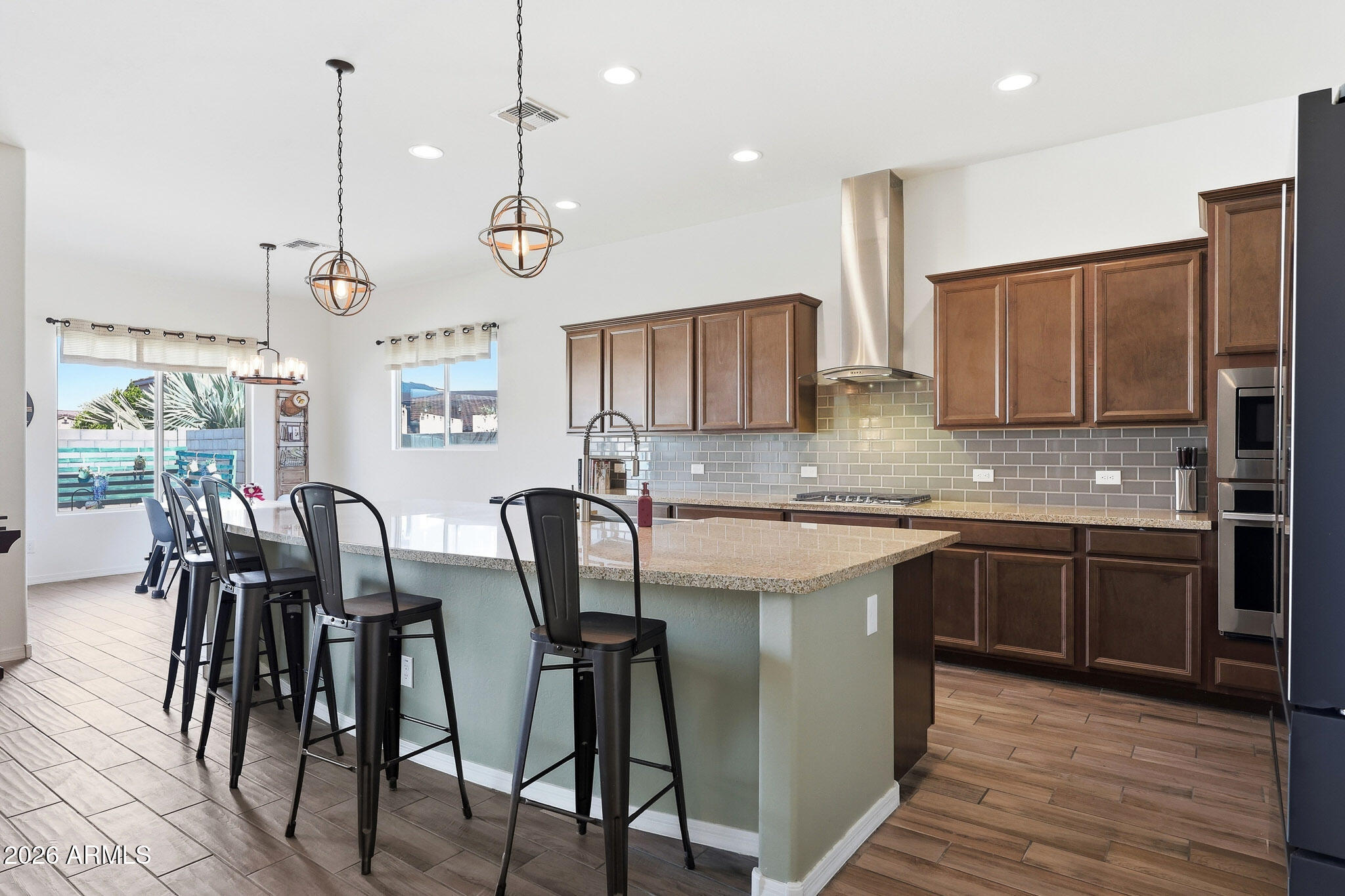 SELLER HAS PAID OFF SOLAR IN FULL! Beautifully appointed single-story home in the desirable Windrose community, featuring newer construction and nearby views of the White Tank mountains. This thoughtfully designed residence offers 4 bedrooms plus an office and 3.5 bathrooms. Step outside to a private backyard with covered patio and self-cleaning PebbleTec pool including a custom Katchakid pool cover. The lot is positioned with North/South exposure, while neighboring single-story homes border the backyard to offer ultimate privacy. A front gated courtyard with built-in fireplace creates an inviting entry, and a 3-car garage completes the home. A wonderful opportunity to own a well-appointed home in sought-after Litchfield Park. Inside, enjoy tray ceilings along with a spacious open kitchen featuring granite countertops, gas cooktop, oversized island, and walk-in pantry. One secondary bedroom is privately situated at the front and includes its own en-suite bathroom, ideal for hosting guests. Custom flooring in three of the bedrooms and the den adds a contemporary touch. The primary suite features an oversized walk-in shower, large separate dual vanities, and soaking tub. The primary bedroom and two of the secondary bedrooms offer walk-in closets. Solar system owned outright, APS bills average approximately $90/month.