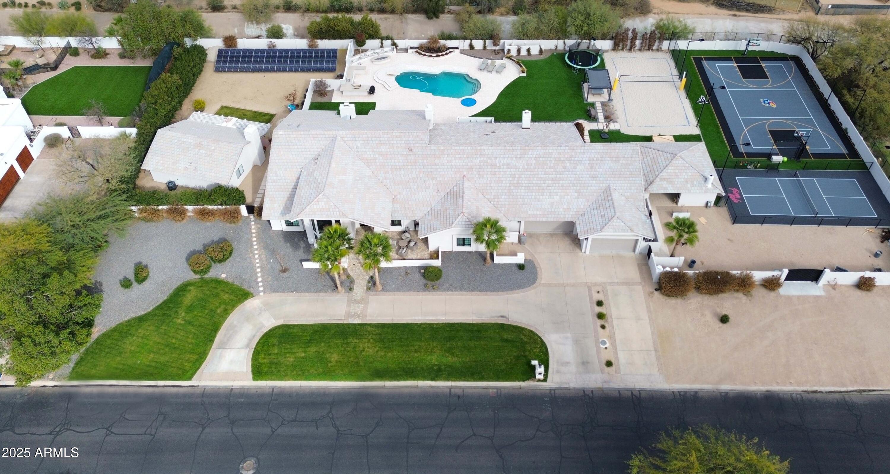 Absolutely stunning updated property showcasing endless on-trend features and an incredible resort-style backyard. Situated on a premium 1.4-acre corner lot, this single-level home boasts a governor's drive and lush landscaping that offers exceptional curb appeal. The unmatched backyard oasis includes an extended covered patio with ceiling fans, a sparkling pool and spa with outdoor shower, expansive grassy areas, a shaded ping-pong space, cozy firepit with seating, three drinking fountains, and a massive multiple gazebos complete with fireplace, TV, BBQ, and a full outdoor kitchen. Perfect for sports lovers, the full-court basketball court, pickleball court, and sand volleyball court are fully lit with professional-grade lighting. The chef's kitchen features wood-beamed ceilings, custom cabinetry with glass inserts, quartzite countertops, Zellige tile backsplash, double islands, a 36" side-by-side fridge and freezer, Thermador gas range with griddle, china cabinet, and an oversized walk-in pantry with built-in cabinetry. The spacious great room impresses with soaring 18' vaulted ceilings, a charming fireplace, a full wet bar with seating, and floor-to-ceiling 20' patio doors that open up to create the ultimate indoor/outdoor entertainment space. The luxurious master suite offers a private patio exit, vaulted beam ceilings, gas fireplace, dual walk-in closets, a secure safe room, and a spa-like bathroom with dual sinks, makeup vanity, custom backsplash, freestanding tub, mini fridge, and an oversized walk-in shower with multiple rain shower heads. Additional upgrades include European white oak flooring, formal dining with a climate-controlled wine display, five newer AC units, whole-home water filtration, solar panel field, new windows with shutters and electric shades, a 5-stall garage, and a home office den with built-ins and a gas fireplace. The one-of-a-kind laundry room is loaded with functionality, featuring four laundry units, custom cabinetry, Kingsbottle beverage cooler, built-in dog kennel and feeding station, and a utility sink. The detached 1guest house adds even more value, complete with a great room, fireplace, full kitchen, two bedrooms, and a full bath. This is the fully loaded dream home you've been waiting for!