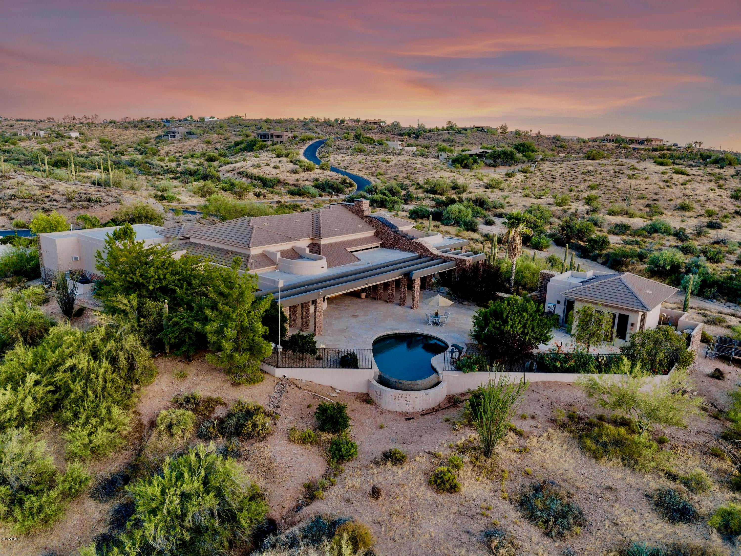 Striking custom contemporary retreat perched atop 4 acres with breathtaking mountain views.  Grand living and dining spaces overlook an expansive resort backyard perfect for private gatherings of all sizes.  Chef's kitchen with large island, granite counters, custom cabinets and walk-in pantry.  Breakfast room offers curved wall of windows. Huge 1,100 sq. ft. split master retreat with sitting area, his and hers walk-in custom closets and exercise space.  Split second master suite. An office befitting the CEO with views to inspire. Detached spacious guest house is perfect retreat for visitors.  Three car extended garage with attached wood working shop.  Watch sunset video tour of property. No steps in home or on patio - true one level living. Furnishings available in separate bill of sale