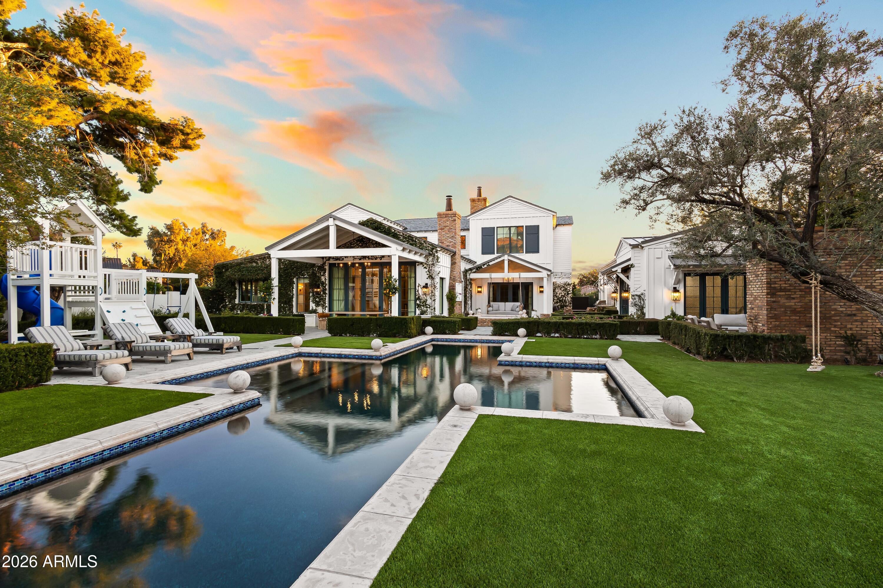 Situated on a quiet cul-de-sac in Arcadia Proper and within the highly sought-after Hopi school district, this exceptional estate rests on an expansive half-acre-plus lot. Originally built by Santorini Homes and newly remodeled by GM Hunt, the residence is complemented by lush, professionally designed landscaping by Refined Gardens and Roots Up, creating a private and timeless setting. The two-story main home features five generously sized bedrooms, each with its own en-suite bath, and a light-filled open-concept layout designed for both everyday living and entertaining. Wide-plank wood flooring, French doors, and refined architectural details connect the living spaces seamlessly. The great room, anchored by a brick gas fireplace, flows into the formal dining area and chef's kitchen, where paneled ceilings, reclaimed wood accents, and premium finishes elevate the design. The main-level primary suite offers a true retreat with a gas fireplace, custom built-ins, and private access to the backyard. The spa-inspired bath includes dual vanities, a soaking tub, an oversized shower, and a custom walk-in closet. Outdoors, the property delivers a resort-style experience with a heated pool and spa, sport court, mature landscaping, and picturesque Camelback Mountain views. Every element has been carefully curated to balance privacy, beauty, and functionality. A detached wellness and batting facilityfully plumbed and HVAC-equippedadds rare versatility. This flexible space may remain a private fitness and training center or be converted into a separate guest house, offering exceptional long-term value. Ideally located just minutes from premier resorts, golf, upscale shopping, and fine dining, this Arcadia estate presents a refined lifestyle opportunity in one of Phoenix's most coveted neighborhoods.