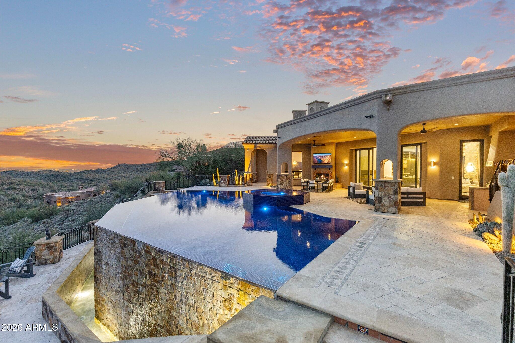 An architectural achievement reimagined by Jaque Bethke on an elevated 1+ acre lot in FireRock Country Club. This 6,007 SF, 5 Bed, 4.5 Ba, museum-quality residence blends raw elemental beauty with world-class technology. Anchored by three 3,000lb motorized amethyst/pink geodes, the home offers seamless single-level living via private elevator. Chef's kitchen features a 12' waterfall island & AI-powered hood. Wellness primary suite boasts Red Mountain views, 4-zone heated floors & steam closet. Fully automated via Josh AI, Control4 & Lutron. The ''Collector's Dream'' garage features 4 over-height, extended-length bays prepped for lifts to accommodate up to 8 cars. Entertainer's backyard with negative-edge pool & spa overlooking Four Peaks & city lights. This is a curated journey in the Sonoran Desert, designed for effortless living and sophisticated entertaining.  The entire living experience is contained on a single main level. The culinary hub is a masterpiece of form and function, a 48" gas range, custom steel and light AI powered hood, and a high-utility butler's pantry. Adjacent to the casual living areas, the home offers a state-of-the-art home theater with a 10-foot screen, an executive home office, and guest suites featuring private balconies. Residents can enjoy the warmth of a sleek fireplace while taking in unobstructed, sweeping views of Red Mountain, creating a resort-level atmosphere within the home. With Smart Home technology, every element of the home's environment, from lighting and climate to security and media, is integrated for intuitive use.  The "Entertainer's Dream" backyard is designed to showcase Arizona's natural beauty. Expansive travertine patios offer a front-row seat to spectacular sunsets, shimmering city lights, and iconic views of Four Peaks and Red Mountain. With a built-in BBQ and multiple lounging zones, the outdoor space is an extension of the home's elemental luxury, completing this architectural masterpiece.