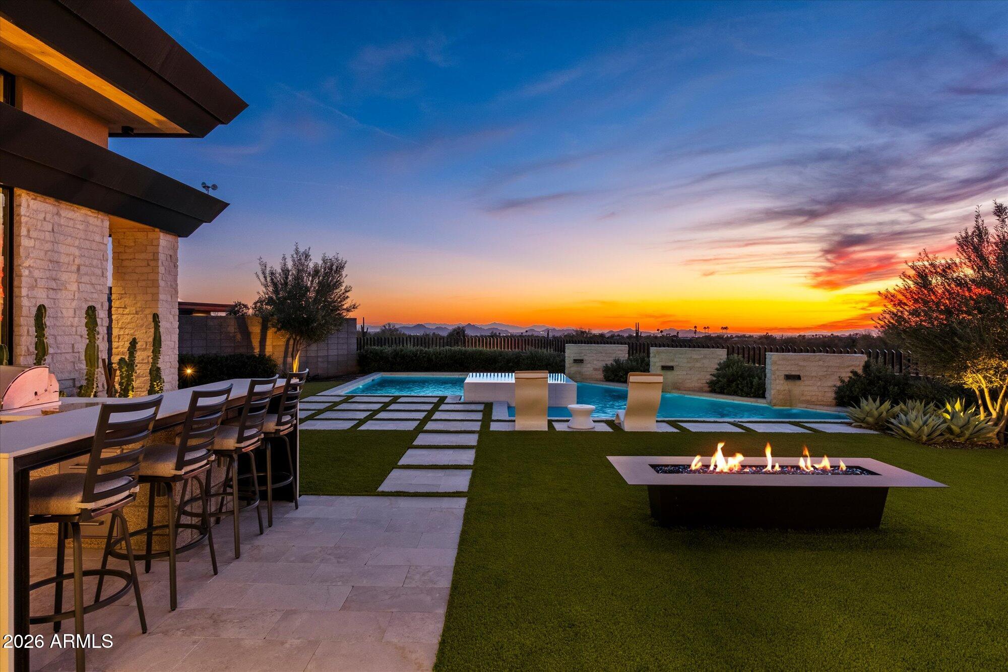 Luxury in Solitude! Gated enclave of just 33 contemporary homes by Swaback Architects & Sonora West Development, North Scottsdale. This stunning single-level residence, built 2021, offers 5,358 sq ft of sophisticated living on a premium acre+ lot with unobstructed views of Pinnacle Peak, Camelback Mountain, and twinkling valley lights. Open great room with soaring wood-plank ceilings, fireplace, gourmet kitchen with Sub-Zero/Wolf appliances, two massive islands, quartzite leather-finished counters. Serene primary suite with spa bath, soaking tub, rain shower. Den/office boasts dramatic open-corner disappearing sliding glass doors; large sliders open the resort-style backyard with ceiling-heated patio. Minutes to Troon golf, Kierland, trails. Prime booming location. Move-in ready elegance.