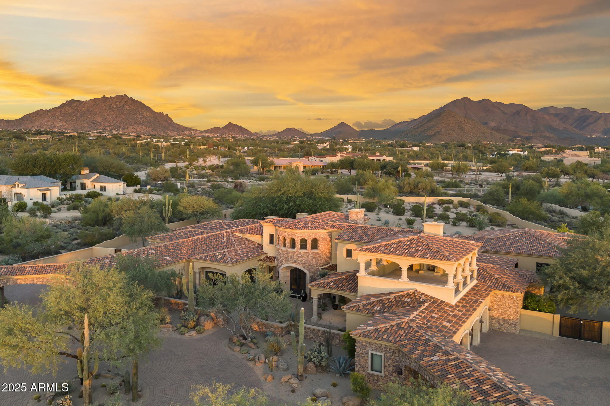 Nestled within the prestigious gated enclave of Prado Estates, this masterfully crafted Mediterranean estate by renowned Calvis Wyant Luxury Homes commands a breathtaking 5-acre elevated parcel with sweeping mountain vistas, glittering city light views, and spectacular sunset panoramas. The main residence spans over 8,000 square feet of sophisticated living space, featuring four generous bedrooms, soaring ceilings that create an atmosphere of grandeur, and a top-of-the-line private theater for cinematic indulgence. A dedicated teen retreat provides the perfect sanctuary for younger family members, while the gracious second-level patio serves as an idyllic perch for sunset gatherings and entertaining beneath the stars. Complementing the main house, a nearly 2,000 square foot guest residence offers two bedrooms, a den, and a private office, ideal for extended family, guests, or a work-from-home haven. The automotive enthusiast will appreciate the rare oversized six-car garage with extra-deep bays perfect for accommodating lifts, abundant storage, and a dedicated workshop space. Outside, the expansive manicured lawn creates an incomparable canvas for grand events or casual family gatherings, while the resort-style pool and spa, paired with a fully appointed outdoor kitchen, define the art of alfresco entertaining. This is more than a home, it's a private estate where luxury, space, and timeless Mediterranean elegance converge to create an unparalleled lifestyle in one of Scottsdale's most coveted communities.