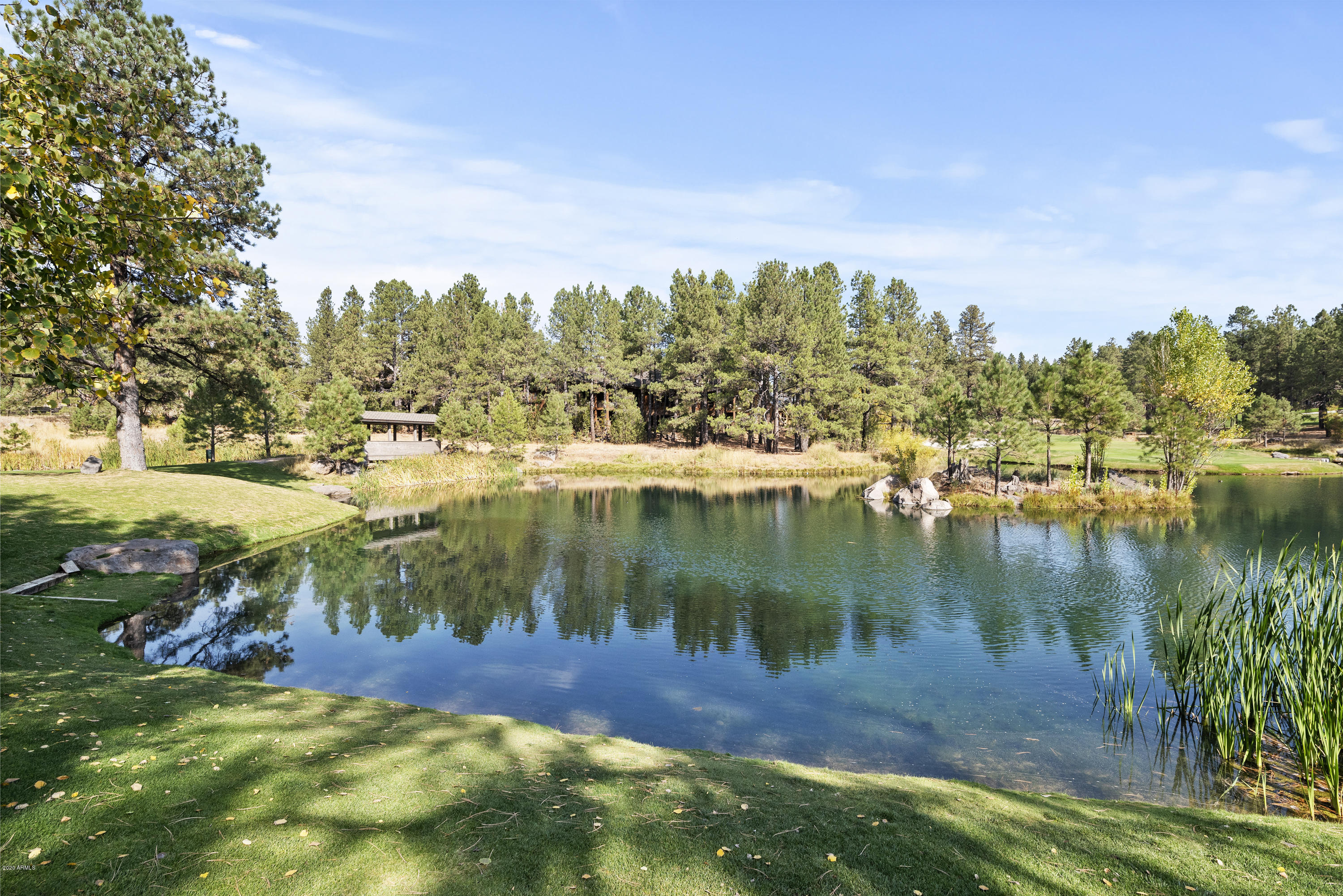 Exquisite executive home in Forest Highlands, situated on a private cul-de-sac with expansive views of the signature 14th hole of the Canyon Course and lake.  No detail has been overlooked in this meticulously-tended retreat—with an open concept, it is at once welcoming and comfortable, while also being thoughtfully-designed and tastefully-appointed.  Hand-crafted stained glass encases the front entry, leading directly into the living area with floor-to-ceiling windows showcasing the golf course and lake—the home was designed to take full advantage of these beautiful views.  A 3-way fireplace warms the gracious living space, with the chef's kitchen just beyond, complete with 6-burner gas stove, built-in appliances, and huge island with breakfast bar. A wonderful morning room off the kitchen invites a cozy start to the day with its own fireplace. Additionally, there is a formal dining area and full wet bar for entertaining, with quick access via a private stairwell to the temperature-controlled wine cellar below.  Just up from the main level is an en suite guest quarters on one end of the living space, with its own private covered deck. The inviting master suite is on the main floor as well, complete with gas fireplace, expansive views and access to its own covered deck. The master bath is complete with steam shower, separate jetted tub, his and hers vanities and toilets, as well as a dressing area in the encompassing walk-in closet.  More thoughtful design elements include a private office, a laundry and utility room on the main level, as well as a laundry room in the lower level of the home, where a second wet bar/small kitchen and living space allow for more relaxing or entertaining.  In this lower level there are an additional 3 spacious bedrooms, all with excellent views of the course and lake.  Numerous covered decks allow for comfortable enjoyment of the spectacular seasons of northern Arizona, but it's the very private main deck that offers such a special space for coming together - with a fireplace, TV, ceiling fan, built-in grill and spacious seating areas, you will spend countless hours enjoying the fresh, mountain breeze off the 13th fairway.  Complete with 3-car garage, dog run and huge uncovered patio, this is truly a legacy property.