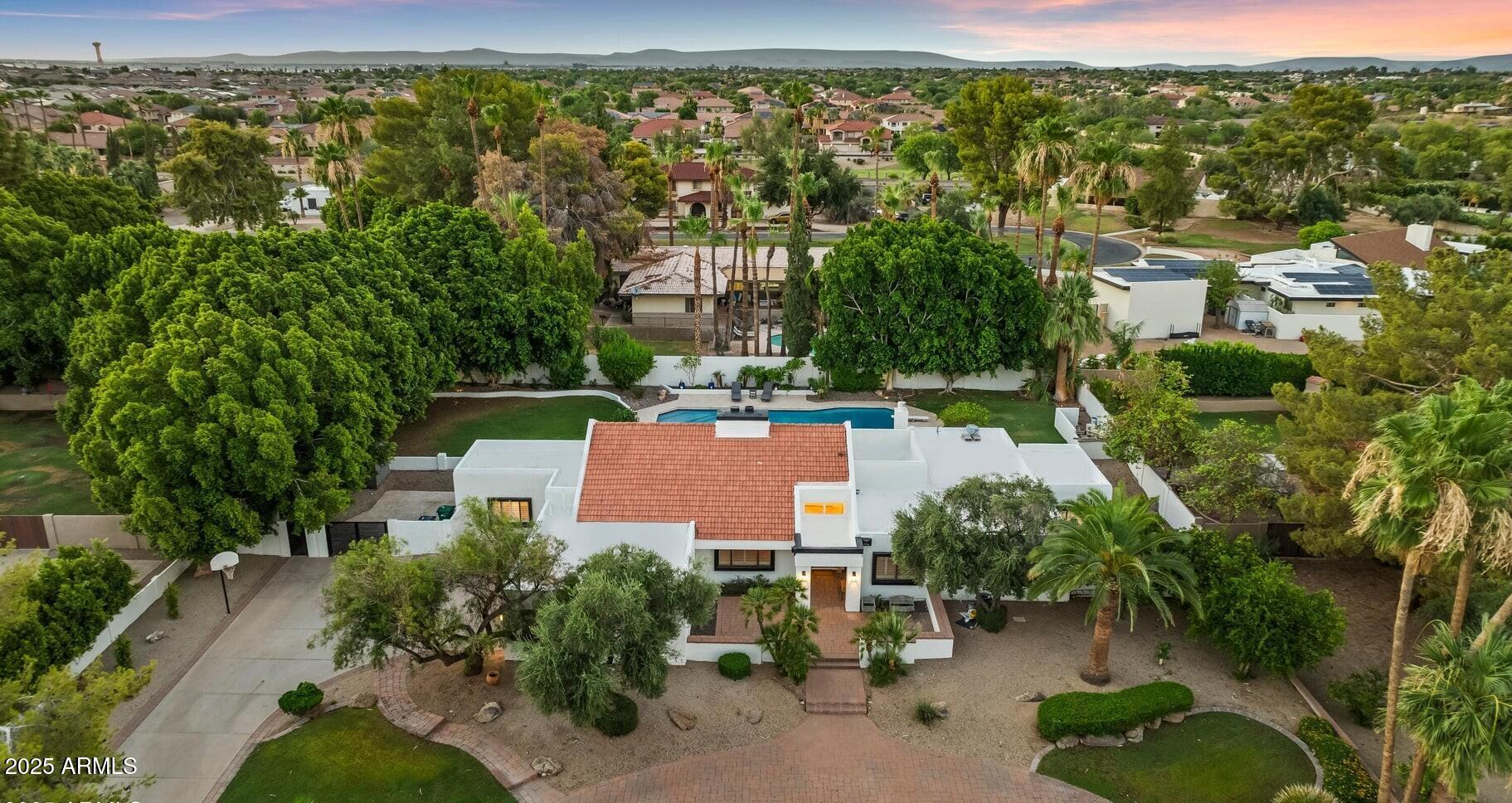 Welcome to this stunning home on a quiet cul-de-sac in the heart of Old Litchfield Park. Situated on over half an acre, this 4-bedroom, 3-bath, 3,466 sq ft home blends timeless charm with modern updates. Enjoy soaring ceilings with exposed beams, a two-sided fireplace, and a chef's kitchen with granite counters and luxury appliances. Step outside to your private oasis featuring a diving pool with a negative-edge waterfall and spa, surrounded by lush landscaping. Circular driveway, two-car garage, and premier location complete this rare find!