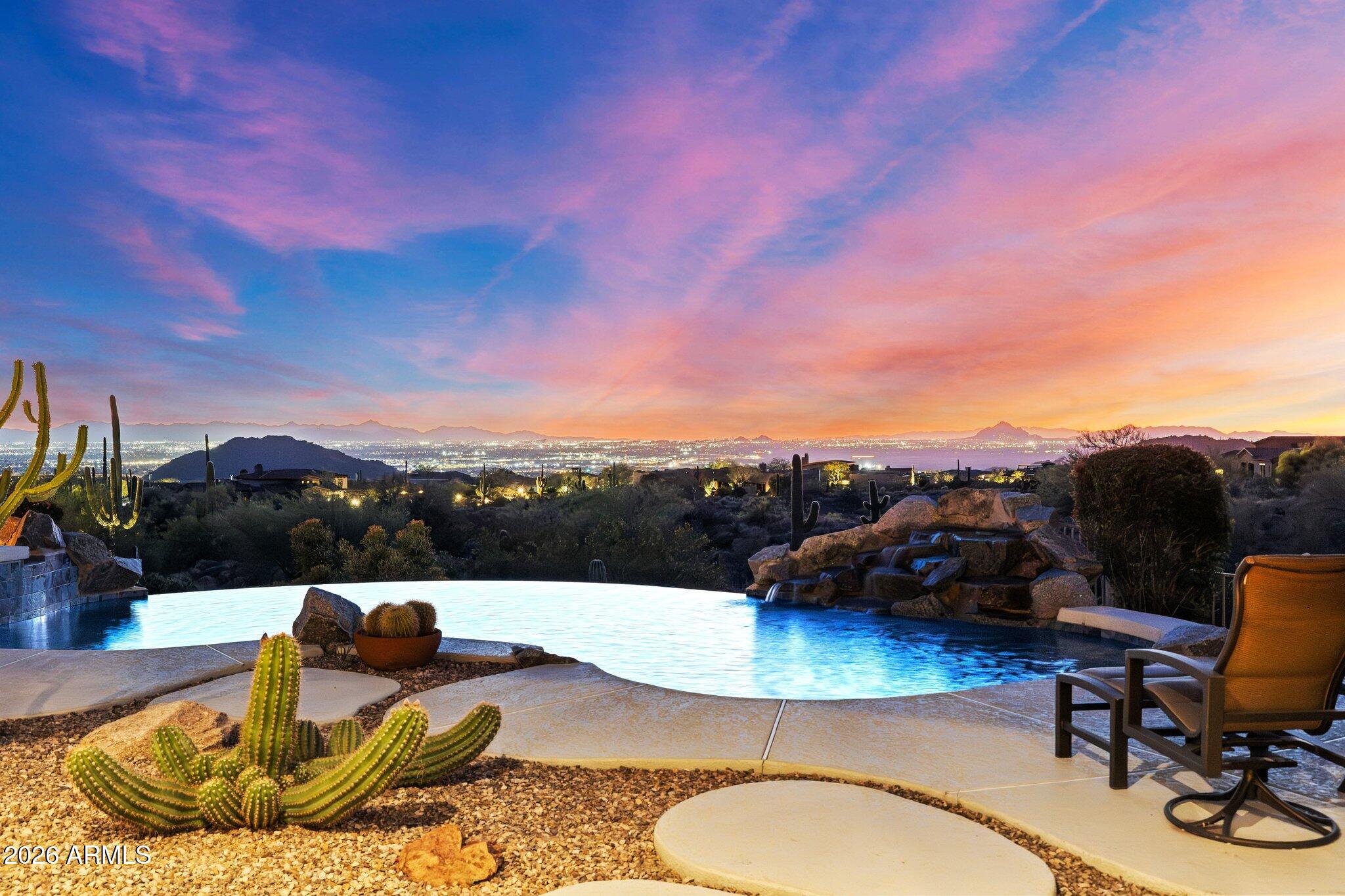 This Diamond Point estate captures sweeping Phoenix Valley views to Camelback Mountain and beyond, with brilliant city lights shimmering across the desert sky at night. Located in the prestigious and gated Diamond Point enclave of Las Sendas, this distinctive Southwest residence welcomes you through a curated desert cactus garden that creates a sculptural sense of arrival. Inside, timeless architecture features soaring ceilings highlighting exposed wood vigas, and graceful curved walls opening to the inviting patio, pool, and spa for relaxing and entertaining beneath desert skies. Enjoy life in Las Sendas, one of Northeast Mesa's premier master-planned communities with resort amenities and easy access to the Tonto National Forest, the Salt River and Saguaro Lake. Convenient to Sky Harbor for quiet mornings, sunset gatherings, and evenings beneath expansive desert skies. Life in Las Sendas places you within one of Northeast Mesa's premier master-planned communities, offering resort-style amenities while surrounded by the extraordinary natural beauty of the Sonoran Desert and a Robert Trend Jones designed championship golf course. Tonto National Forest, the Salt River, and Saguaro Lake are all just minutes away, creating endless opportunities for hiking, boating, kayaking, tubing, and exploring the landscape that makes this corner of Arizona so special. Convenient to Phoenix Sky Harbor International Airport and Phoenix-Mesa Gateway airports. Nearby hospitals, medical centers, shopping destinations, restaurants, and everyday services ensure that residents enjoy both tranquility and convenience. The location provides easy access to the amenities and opportunities of the Valley while maintaining the sense of retreat that makes Las Sendas such a desirable place to live.
For those seeking a home that combines architectural character, extraordinary views, outdoor living, and a vibrant community environment, this Diamond Point residence represents a rare opportunity within one of the Phoenix Valley's most distinctive neighborhoods.