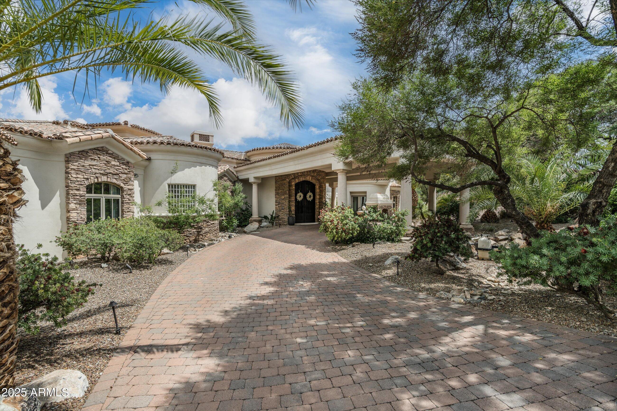 This custom estate offers the perfect balance of thoughtful design and relaxed sophistication. From the moment you walk in, the transformation is undeniable. Architectural levels have been removed to create seamless lines, enhancing the natural flow with newly installed wide-plank flooring. Oversized picture windows frame sweeping views and fill the home with light, connecting every room to the surrounding landscape. At the center of the home is a stunning designer kitchen—sleek yet functional—with high-end appliances, a stone-wrapped bar, and dual fireplaces that bring warmth to the adjacent living areas. The open layout is ideal for entertaining, with French doors opening to a newly built outdoor kitchen, full bar, and a cozy fireplace, expanding your living space year-round.