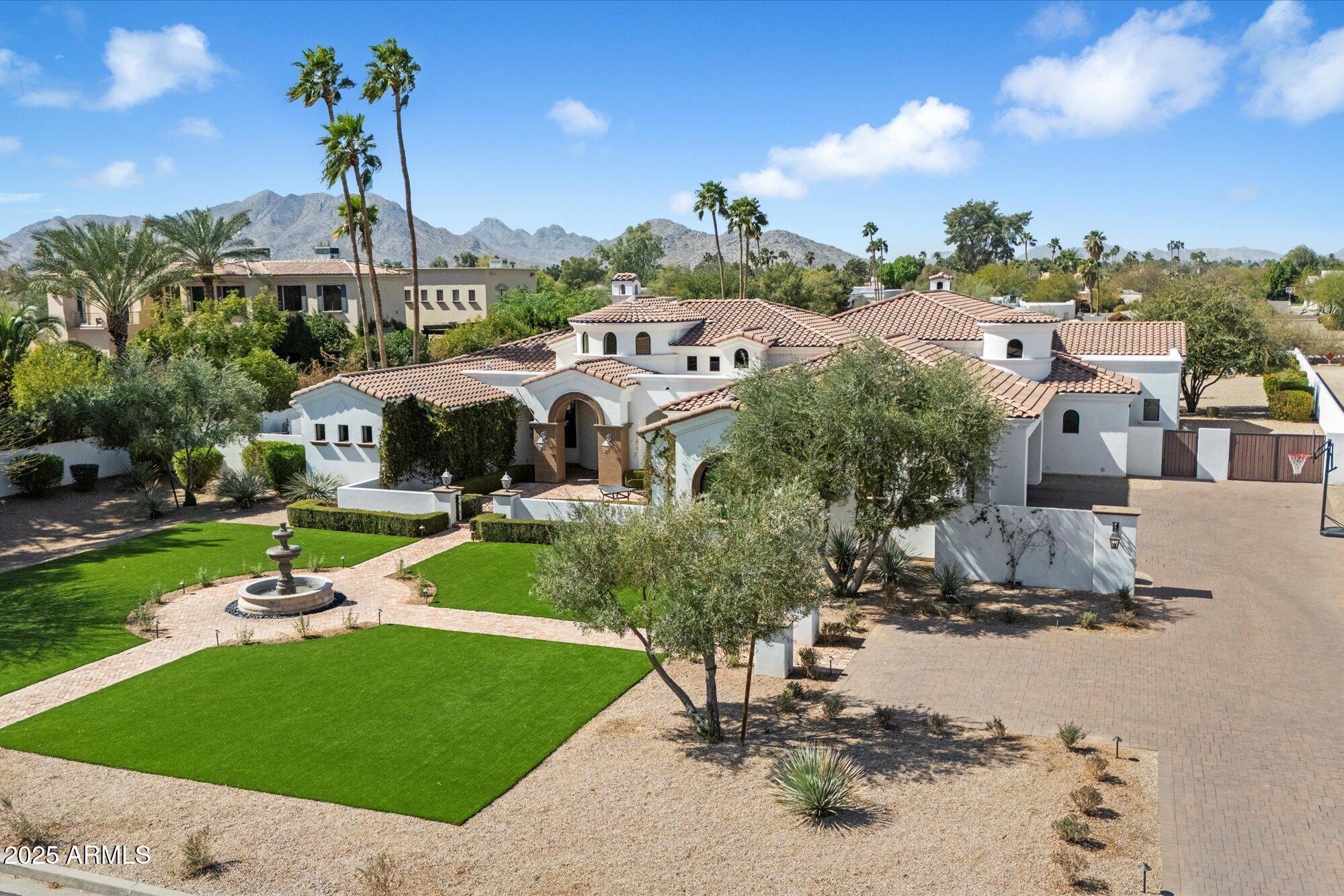 Experience grandeur in this 5,561 sq. ft. Mediterranean estate, a rare find in Paradise Valley's Country Club Acres and the prestigious 3 C's Scottsdale School District. Move-in ready and designed to impress, this 5-bed, 4.5-bath home features soaring 14-16 ft. ceilings, expansive windows, hand-laid wide plank flooring, limestone fireplaces, and designer finishes. The primary suite offers his-and-hers closets and a spa-inspired ensuite with dual vanities, a soaking tub, and a spa shower. The chef's kitchen boasts two islands, Wolf/Sub-Zero appliances, a butler's pantry, and a wine fridge. Set on 52,932 sq. ft., enjoy a resort-style pool, heated spa, patios, pickleball court space, and a putting green. A 4-car garage with an EV charger completes this luxury home.
