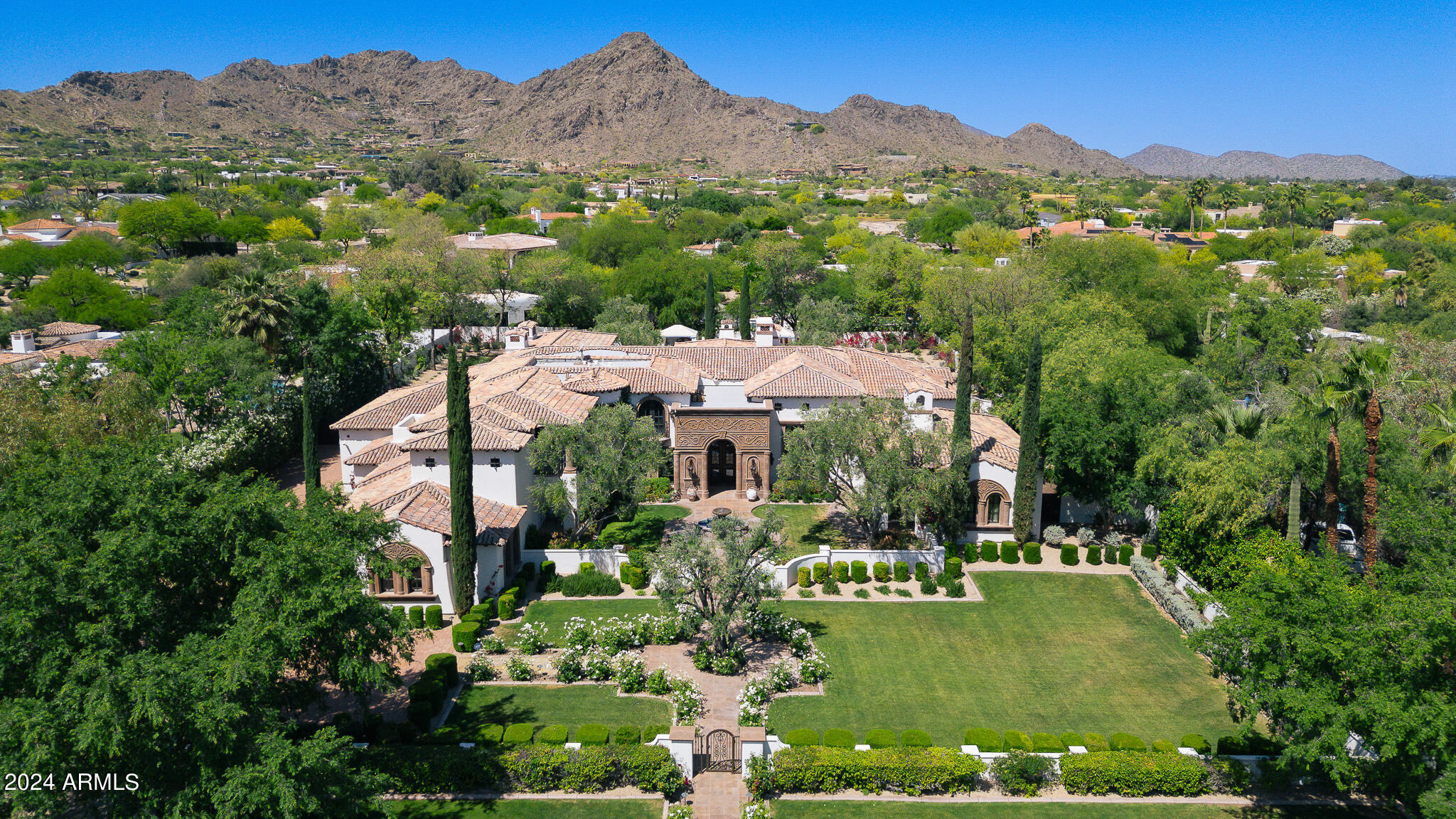This stunning estate in Paradise Valley greets you with dramatic landscaping and lush lawns, effortlessly merging timeless charm with modern sophistication. Spanning 8,369 sq ft, the main house and separate casita are designed with meticulous attention to detail, featuring a barrel-vaulted herringbone brick ceiling in the kitchen, hand-carved wood beams in the living room, beautiful arched hallways, and exquisite stone and wood flooring throughout. Transform movie nights with the lavish custom theater and game room, ideal for gatherings with family and friends on warm summer days. Retractable glass walls in both the family and living rooms open to a resort-style backyard, complete with two custom cabanas overlooking a glass-tiled pool and expansive lawn. The primary suite, nestled in its own private wing, offers a cozy sitting area, an ultra-luxurious bath, custom his-and-hers closets, an exercise room with a wet bar, and a secluded patio. Down the grand arched hallway, you'll find the formal dining room adjacent to a wine cellar, as well as an impressive office featuring coffered wood ceilings and its own private patio.