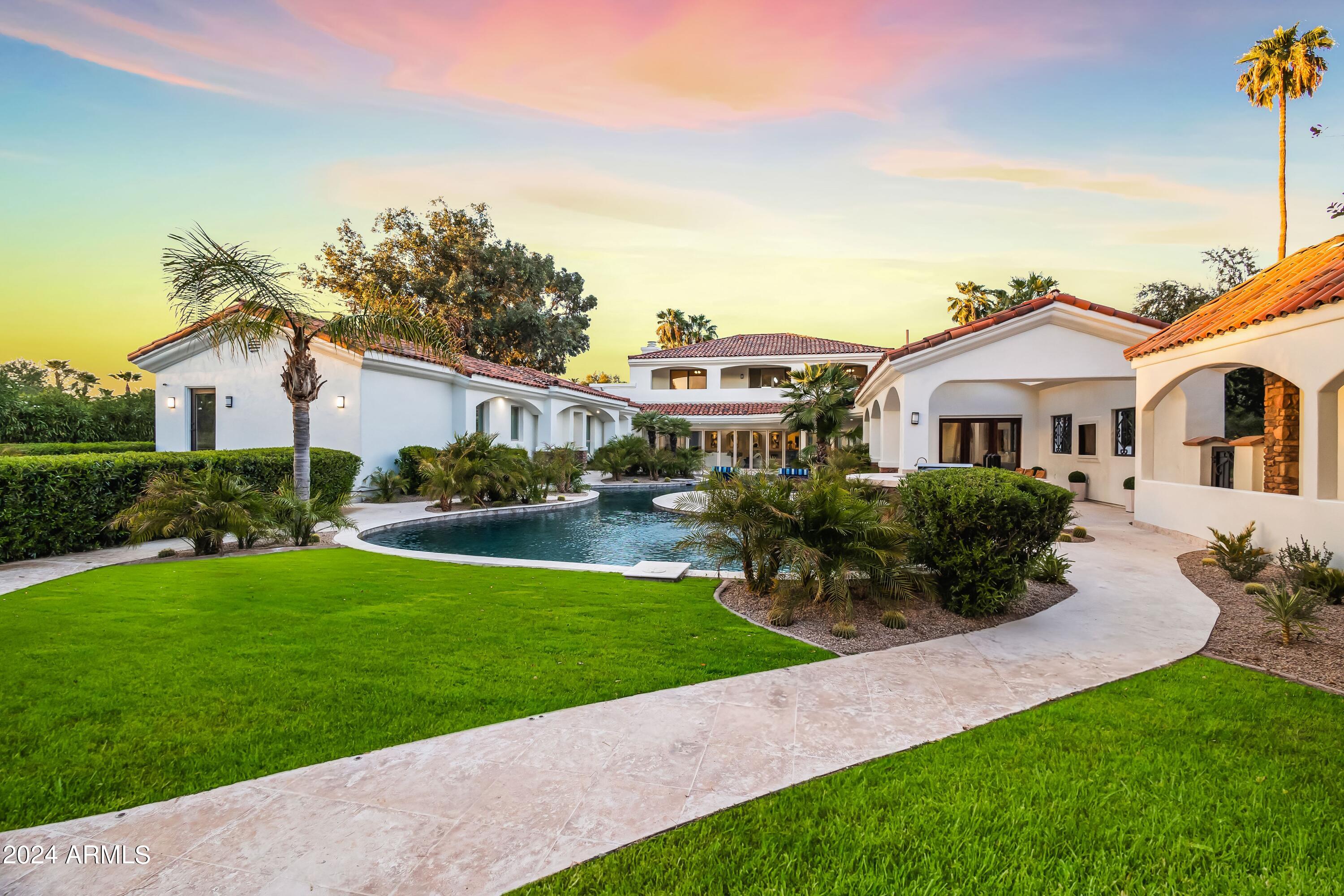 This stunning custom-built estate seamlessly blends luxury and sophistication with comfort and entertainment. Featuring a private gated entrance for utmost privacy and security. This home boasts six spacious bedrooms, six elegant baths, on over an acre of lush grounds adorned with palm trees and captivating fountains. As you pass through the private gates, you'll be greeted by a grand motor court leading to beautifully handcrafted entry doors. The expansive 1,200-square-foot great room showcases LED backlit coffered ceilings and 30 feet of retractable glass doors, merging indoor and outdoor living. Enjoy a private beach and lagoon-style pool, surrounded by vibrant gardens, a secluded spa, a circular fire pit, and a spacious outdoor BBQ area—perfect for hosting unforgettable gatherings. Designed for both casual and formal entertaining, this home features a 12-seat theater with a state-of-the-art Sony 4K projection system, Savant/Apple TV controls, and Dolby Atmos surround sound. The chef's kitchen, equipped with Viking appliances, complements the expansive master suite with its private salon and kitchenette. Wine enthusiasts will appreciate the impressive 1,080-bottle wine cellar. Car lovers will delight in the climate-controlled 2,200-square-foot garage with RV space, capable of housing up to eight cars (or 16 with lifts), currently featuring an indoor pickleball court.
This home is designed for main-level living, featuring five of the six bedrooms, including the spacious primary suite, all conveniently located on the first floor. The second floor offers an ideal space for guests or serves as a generous flex room, perfect for your needs. This layout ensures both comfort and accessibility for everyday living and entertaining.