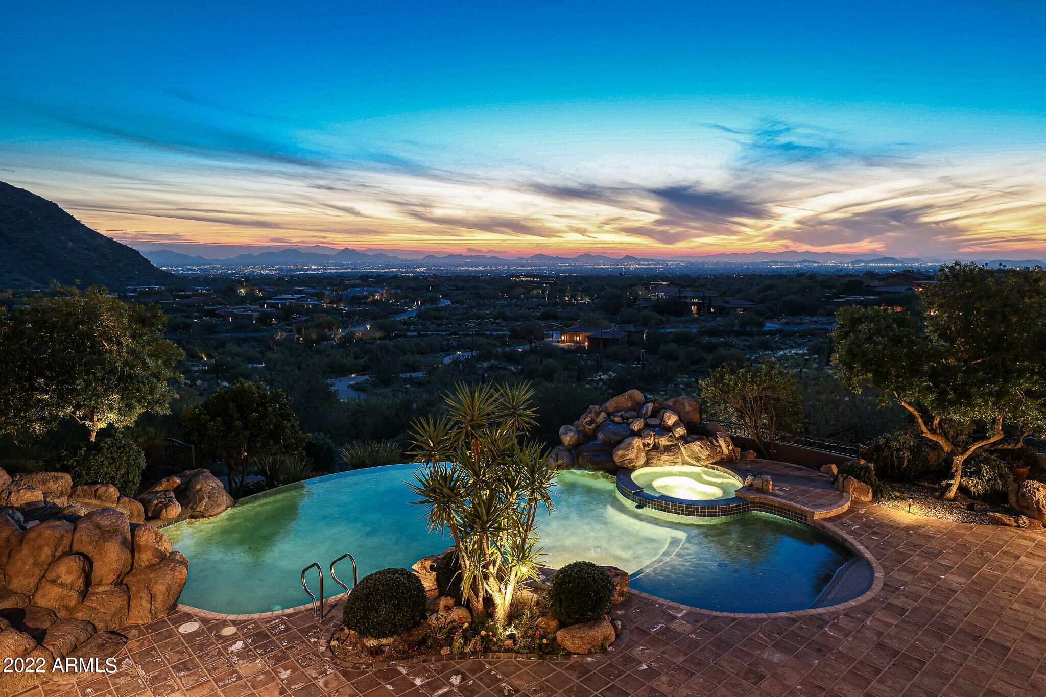This one-of-a-kind private estate is situated on an expansive 14 acres of high Sonoran desert with sweeping, hard to duplicate views of the metropolitan Valley of the Sun below! Sitting at roughly 2,222 ft in elevation above the city and located in one of the premier North Scottsdale communities, Canyon Heights. This intimate gated community of only 34 coveted homes sits on 160 acres and is a hidden gem nestled among the McDowell Mountains Preserve. The estate has its own personal gated entrance connected to a gate house/studio perfect for extended stay guests. The studio has a living area/studio space, a private bedroom, full bath, and is connected to a four car garage. Heading up the hill from the gate house enjoy the local flora and fauna from the winding paver drive. The entry courtyard has a centerpiece Ironwood tree, circular drive, and an additional four-car garage with two large storage rooms. Every car enthusiast will love the 8-car garage total, with the ability to add lifts at the gate house for the potential total of 12 garage spaces.

Encompassing a remarkable 11,340 square feet, this Nance Custom Home was built with entertaining and fine living in mind and houses seven total bedrooms and eight total bathrooms. The custom metal and glass arched front door sets the tone for the arched entryways throughout. The round entry foyer allows you to usher guests into the large living room with soaring ceilings accented with wood beams, cantera stone fireplace, wood floors, two exterior French doors, glass shelf wall display and floor to ceiling windows to maximize the incredible valley and city light view. 

The chef's kitchen is adjacent to the living room and also maximizes the exterior views with large windows bordering the breakfast nook, built-in desk, coffee bar/baking station, walk-in pantry and butler's pantry with dishwasher, beautifully stained cabinetry, custom mural backsplash, stone hood vent, stainless steel appliances including Asko, Dacor, Sub-Zero, and an eight burner Viking stove, and a furniture grade island with sink and countertop seating.

In addition to the kitchen and living room, the main level also boasts a formal dining room with adjacent wet bar (including ice maker), large laundry room with ample storage and counter space, two powder baths for guests, two private offices with wood paneling and details throughout, and two ensuite guest rooms with walk-in closets. Rounding out the main level is the Master suite. With its high ceilings and neutral pallet it feels like a spa retreat. Amenities include a corner fireplace, exterior covered balcony access, his and hers closets with cedar accents and stackable washer and dryer, jetted tub for two, separate sinks one with a built-in vanity, separate water closets, and amazing views.

You can access the lower level of the home from one of the two staircases or the elevator. Featured in the lower level is a large great room, full kitchen including all appliances, breakfast nook with built-in seating, movie theater, one ensuite bedroom with attached Murphy bed, another bedroom with adjacent bathroom with steam shower currently being used as a gym, storage room housing all the smart home components (security, lighting, sound), and a large air-conditioned wine room with security door, easily housing over 1,000 bottles.

The exterior spaces are exceptional. Enjoy a six-hole artificial turf putting green with sand trap to practice your chipping. The upper and lower levels each have covered patios that extend the length of the home. The negative edge pool features a beach entry, water slide, natural boulder waterfall, and elevated spa with stunning views. The guest house can be accessed from either the backyard or the service stairs and comes with a full kitchen, living room with fireplace, bedroom with attached bath and stackable washer and dryer.

Welcome home to North Scottsdale, where you can live in luxurious solitude with upscale amenities just moments away.