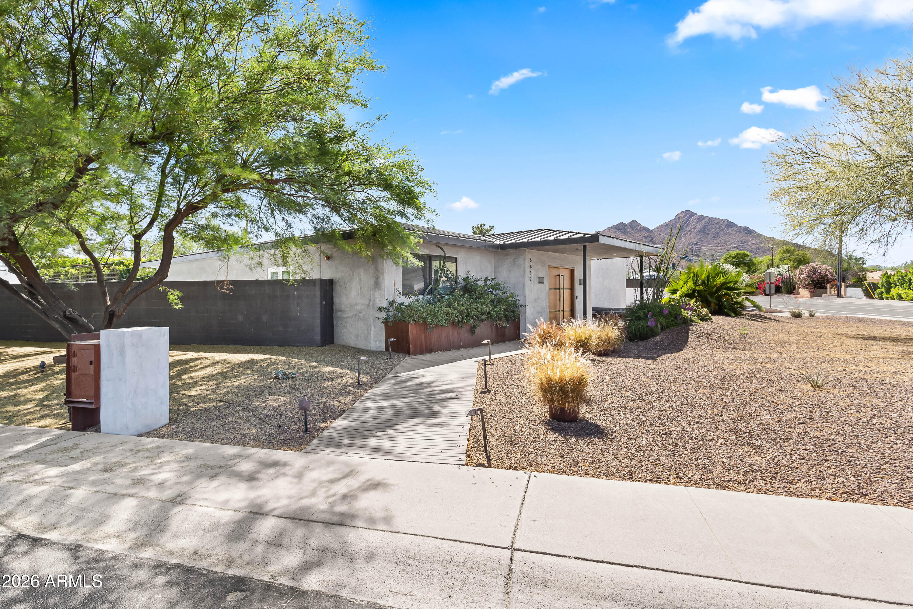 Experience refined desert living in this custom-built modern estate in the heart of Paradise Valley, showcasing breathtaking views of Camelback Mountain. Ideally located just minutes from Old Town Scottsdale, world-class resorts, championship golf, premier hiking trails, upscale dining, and luxury shopping. Designed with a focus on modern luxury and low-maintenance living, this 4-bedroom, 3-bath residence offers over 3,400 sq ft of thoughtfully curated space. The open-concept floor plan seamlessly connects the living, dining, and kitchen areas, highlighted by sleek concrete flooring, soaring 10-foot ceilings, and an expansive wall of sliding glass doors that create effortless indoor-outdoor flow. The chef's kitchen is equipped with stainless steel appliances, multiple ovens, a large center island, and a walk-in pantry--perfect for both everyday living and entertaining. The spacious primary suite features private backyard access, a separate sitting area, a custom walk-in closet, dual vanities, and an oversized walk-in shower. Additional highlights include a 3-car garage with built-in storage and epoxy flooring, as well as dual washer and dryer units for added convenience. Outdoor living is elevated with a rooftop deck offering stunning mountain views, and a resort-style backyard complete with a custom heated pool and spa, covered patio with built-in BBQ, and expansive yard with low-maintenance turf with desert landscaping.