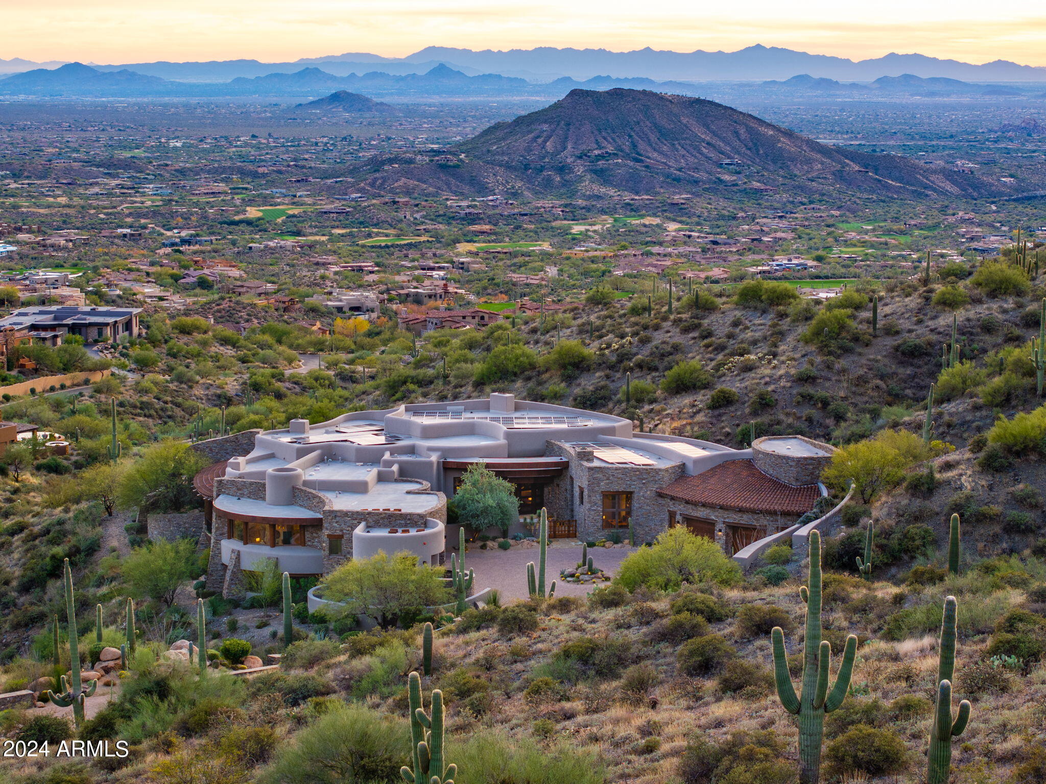 GOLF MEMBERSHIP AVAILABLE. Discover the jaw dropping views and the pinnacle of luxury living in this exquisite custom home, masterfully designed by renowned architect Lee Hutchison. Nestled on a sprawling 9.9 acre lot in the upper village of Saguaro Forest within the prestigious guard gated Desert Mountain golf community, this modern organic pueblo inspired home featuring stone walls has a curvilinear design with 360 degrees of awe-inspiring mountain scenery with Pinnacle Peak as the stunning centerpiece. Enjoy picturesque sunrises/sunsets, spectacular moonrises, distant golf course views and evenings full of sparkling Valley lights. Step inside to the open great room, an entertainer's dream with a gas fireplace, custom crafted Az ash wood bar and a beamed ceiling.
