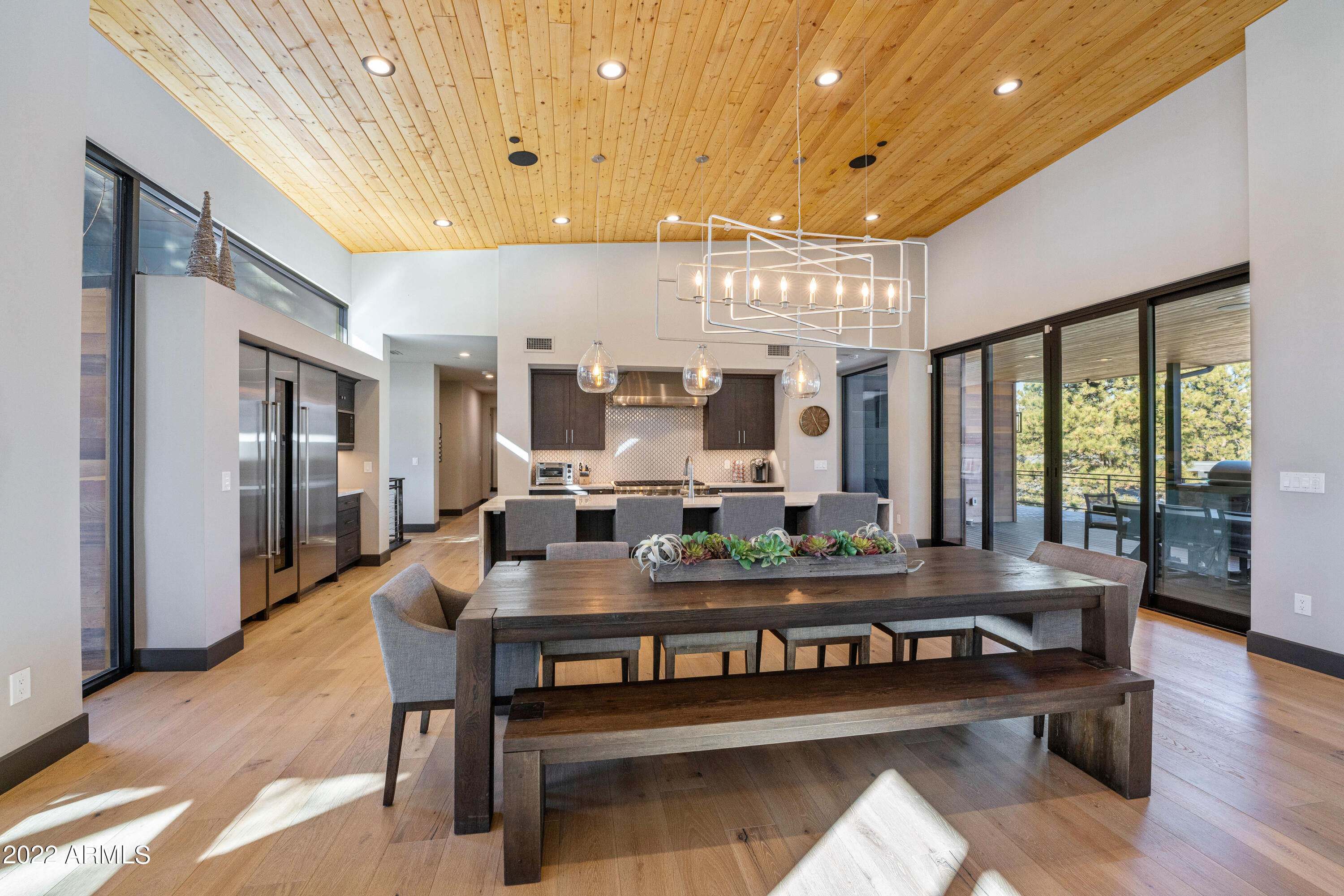 This astonishing contemporary home sits on the 18th tee box of Pine Canyon's award-winning golf course and is truly one-of-a-kind. With 5 bedrooms, 4.5 bathrooms and 2 living areas this home is perfect for entertaining. Upon entering the home, you are greeted by a masterful floor to ceiling stone fireplace accented by tongue and groove ceiling that expands throughout the main level and out to the expansive deck. With views of the San Francisco Peaks, nearby lake and the 18th tee box and fairway the back deck is complete with a built-in BBQ and bar seating. The kitchen is a chef's dream featuring a 6-burner range, double oven, full backsplash, walk-in pantry, a refrigerator-freezer including separate wine refrigerator, and a stunning island with extra bar seating. An additional en-suite guest room and the master bedroom are located on the main level. The master features a separate exit to the back deck, fireplace and grand master bath with dual vanities, large shower, and soaker tub.
The lower level of the home is complete with an additional family room area, that opens up to an enormous patio. With and 2 additional guest rooms a shared bath and a jr. master including a fireplace and separate bath. Additional features include surround sound inside and out, a 3-car garage with epoxy flooring, and access to Pine Canyon's sledding hill right out your back door.