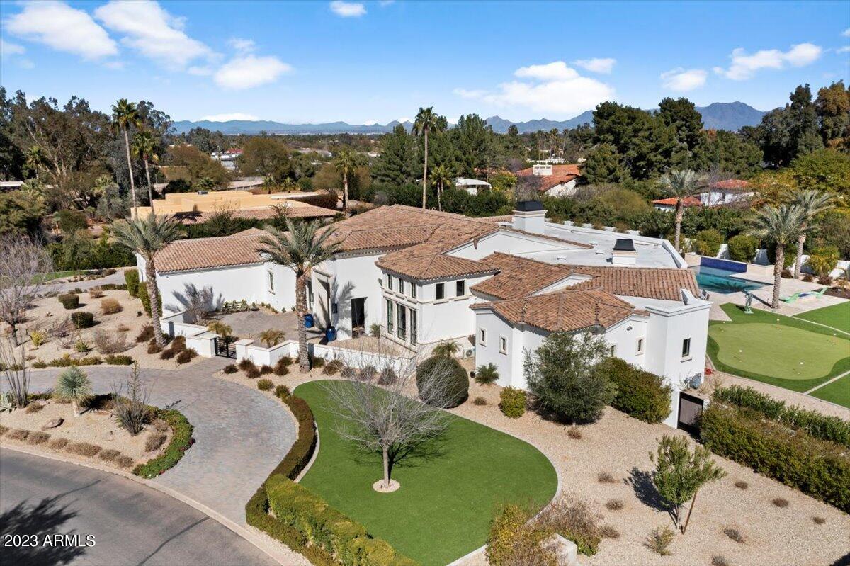 Better than new custom Paradise Valley estate home has been designed for family living and entertaining. Immerse yourself in the huge kitchen with double islands, Sub Zero fridge and freezer, Wolf range and two Bosch dishwashers. Family movie night will never be the same again in the theater room with state-of-the-art Dolby Atmos surround sound, tiered seating and a game room area with a full bar with Sub Zero beverage fridges and an ice maker. The family room features 14' ceilings and a 16' long motorized fully retractable pocket door that connects the indoor spaces with the outside. Enjoy casual dinners or elegant affairs in the formal dining room with butler's pantry and a custom wine wall with Basalt stone, a dedicated cooling system and LED accent lighting. The primary suite is a... true retreat with a centerpiece fireplace and marble en-robed sumptuous bath that includes his and her closets and toilet rooms. The kids wing features a flex room with a shiplap feature wall. The guest suite with its own private courtyard entrance is perfect for your visiting guests. Enjoy the ease and control of owning a Smart Home with Control 4 Home Automation System with touch screen panel that controls the main area lighting, thermostats, cameras, security and audio. The oversized four car garage has insulated garage doors and epoxy floors. Enjoy a resort style setting in the backyard with expansive travertine pavered patios that overlook a custom 5-hole synthetic grass putting green and gorgeous heated pool with three baja steps, cascading water features and a negative edge spa. Enjoy relaxing next to the gas fireplace with Limestone surround or sitting next to the gas fire pit poolside. The large built in BBQ provides ample bar seating to enjoy gazing at the sprawling lawns and garden areas. The captivating finishes of this home include European Oak floors, synthetic stucco, exterior limestone accents, mud set clay tile roof, custom iron gates, custom stone, marble and granite finishes, LED lights throughout, and wood clad Low-E windows. Other remarkable features include two gas tankless hot water heaters, upgraded foam insulation in the exterior walls, insulated interior walls, a high-pressure misting system + so much more in this amazing home!