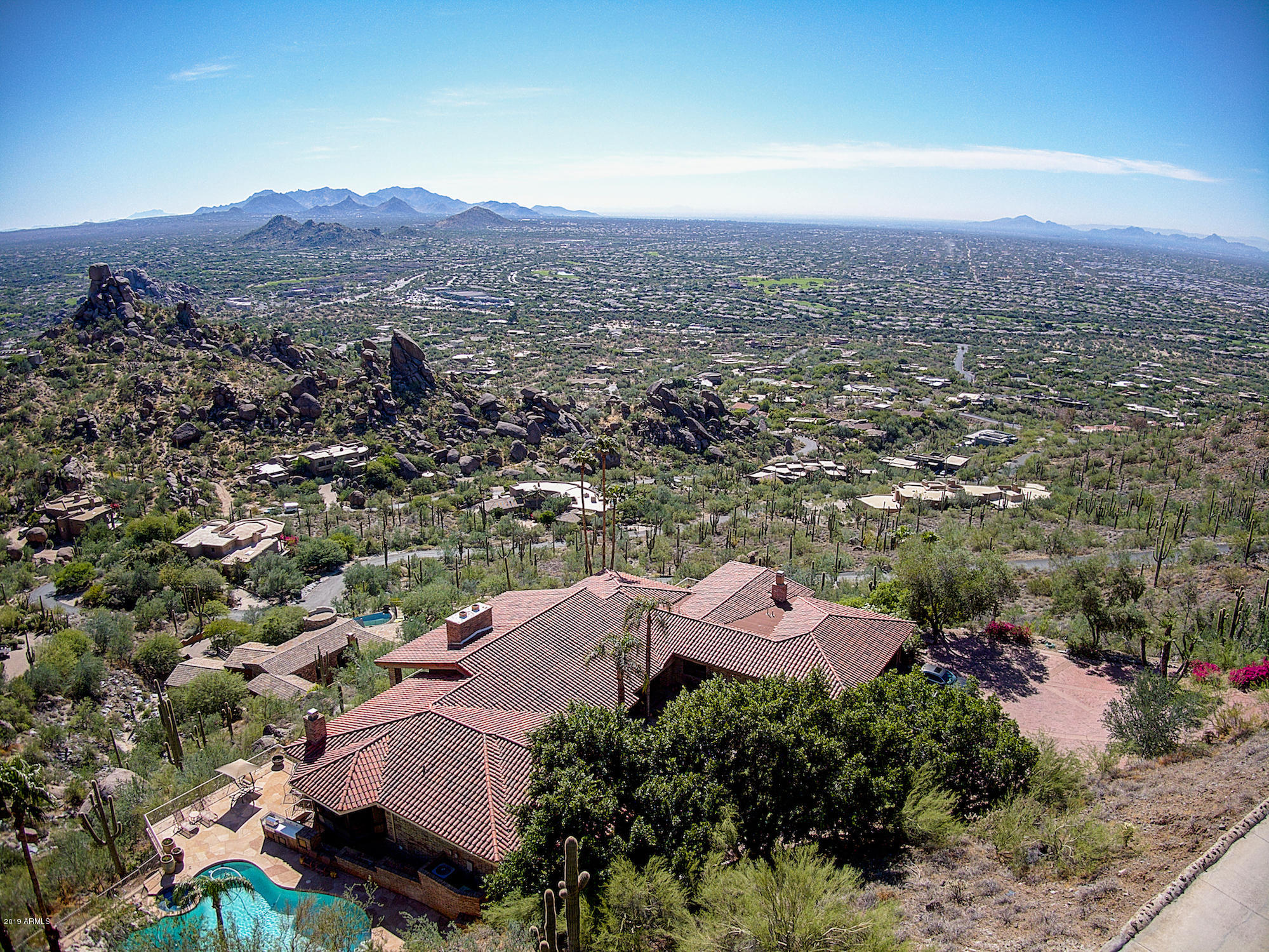 This iconic, exquisitely-remodeled estate ON 10 ACRES offers total privacy and staggering, mesmerizing 50+-mile views of the Valley, Mountains, and towering boulder formations nearby.   The home features a world-class kitchen and family room, with a grand, light-filled living room looking at dramatic sunrises over massive granite boulders.   Notable features:  new front door, hardwood & stone floors, high beamed ceilings, a unique den/bar & an owner's suite with more amazing views and a re-imagined bath that is simply heavenly.   Downstairs, your guests will appreciate two spacious en-suite bedrooms, a huge bonus/family room & separate ''apartment-style'' guest quarters.  And every night, you will love the dazzling display of city lights, dancing across the valley to the distant horizon.