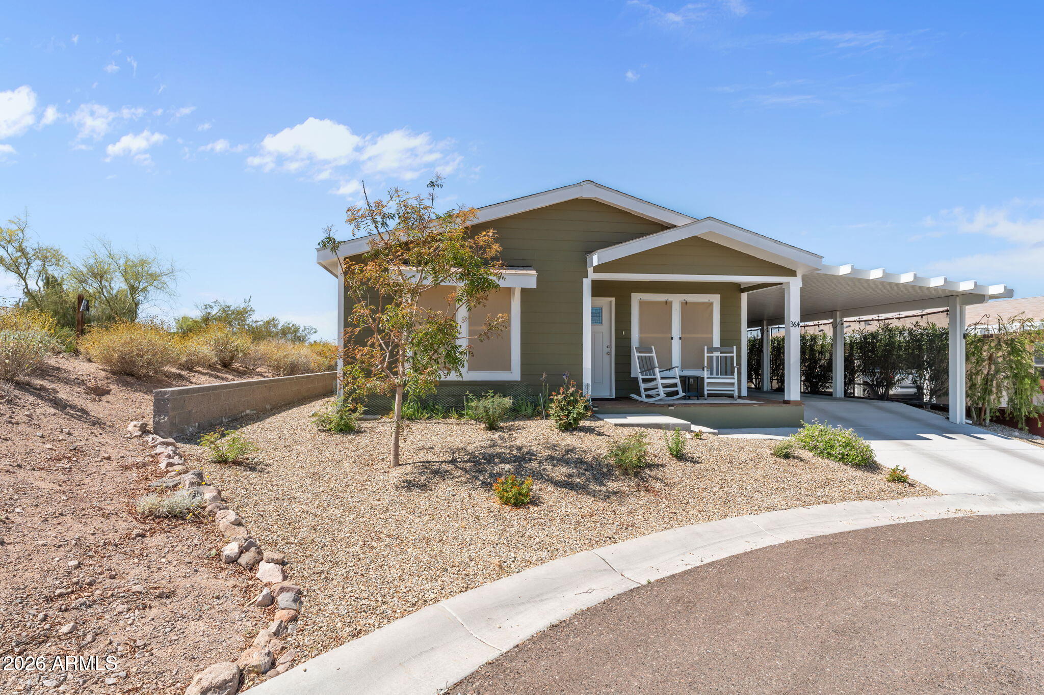 From the moment you arrive, this home draws you in with undeniable charm and an inviting front porch!  Inside, warm tones and natural light create an immediate sense of comfort, while the open-concept design centers around a stunning kitchen with an oversized island and abundant cabinetry.  Step outside and it only gets better. A sprawling covered patio transforms into your own private desert oasis, with extended covered porch, turf, shade screens, open views, and space to enjoy AZ beautiful weather year-round.  Every detail has been thoughtfully curated with easy living in mind including an extended carport and 136 sq. ft. secure storage.  Situated close to the community pool, jacuzzi, exercise gym and clubhouse, make this an ideal location in the desirable Active 55+ Community of West Pa