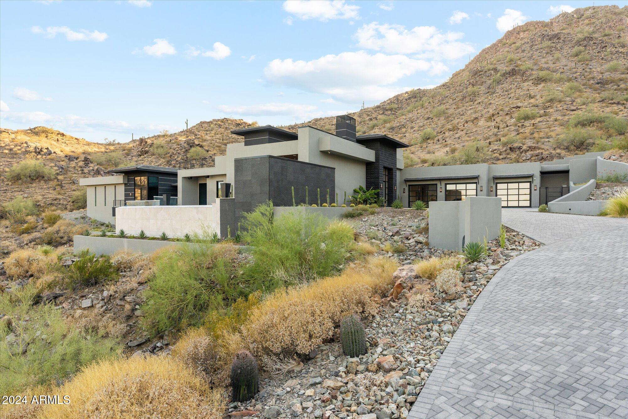 Presenting a stunning architectural masterpiece situated on over 2.5 acres within the exclusive 24/7 guard-gated community of Paradise Reserve. Crafted by Cullum Homes, this two-story contemporary estate offers a luxurious retreat with unmatched views of the majestic Camelback Mountain from every vantage point, creating a tranquil and picturesque setting. Elevated on a hill, the property features a grand driveway leading to a custom 3-car garage with sleek glass doors. Upon entering through the custom glass door, you're welcomed by a beautifully designed great room that seamlessly connects indoor and outdoor living spaces. At the heart of the great room is a designer fireplace that radiates warmth and elegance, while a retractable sliding glass door opens up to breathtaking mountain views. A nearby wet bar with exquisite pendant lighting, a wine fridge, and a custom glass-enclosed wine rack adds sophistication, showcasing your collection in style. The gourmet kitchen is a dream for any culinary enthusiast, equipped with premium Wolf and Sub-Zero appliances, sleek off-white cabinetry, quartz countertops, dual sinks, dual ovens, and a 6-burner gas range. A built-in espresso machine is ready to enhance your mornings, and the adjacent butler's pantry offers ample storage with extra cabinetry and a second refrigerator. Ascend the elegantly designed glass and wood staircase to a captivating loft, featuring an additional wet bar and a built-in entertainment centerperfect for unwinding and relaxation. The master suite combines luxury and serenity, complete with a dual-sided fireplace, sliding doors to a private patio, and endless views. The spa-like master bath features floating vanities, a spacious glass-enclosed shower with rain and handheld showerheads, and a soaking tub set by the fireplace. Multiple windows and a door to the outside provide additional mountain views, creating a tranquil ambiance. A den and office, enclosed by elegant glass doors, offer a peaceful work-from-home space. The additional bedrooms each feature ensuite baths for comfort and privacy. Throughout the home, recessed lighting and surround sound enhance the living experience. Outside, you'll find an enchanting space designed for relaxation and entertainment. The covered patio is perfect for outdoor dining, complete with an outdoor kitchen that includes a built-in BBQ, refrigerators, dishwasher, wall oven, sink, and an island with bar seating. Beyond the patio, a travertine-tiled deck leads to a captivating infinity-edge pool, where the water seems to blend into the sky. The raised spa, featuring one of two outdoor gas firepits, adds warmth and ambiance, all set against the stunning backdrop of Camelback Mountain and city lights.This home is a true masterpiece where luxury and nature unite to offer an unmatched living experience.
