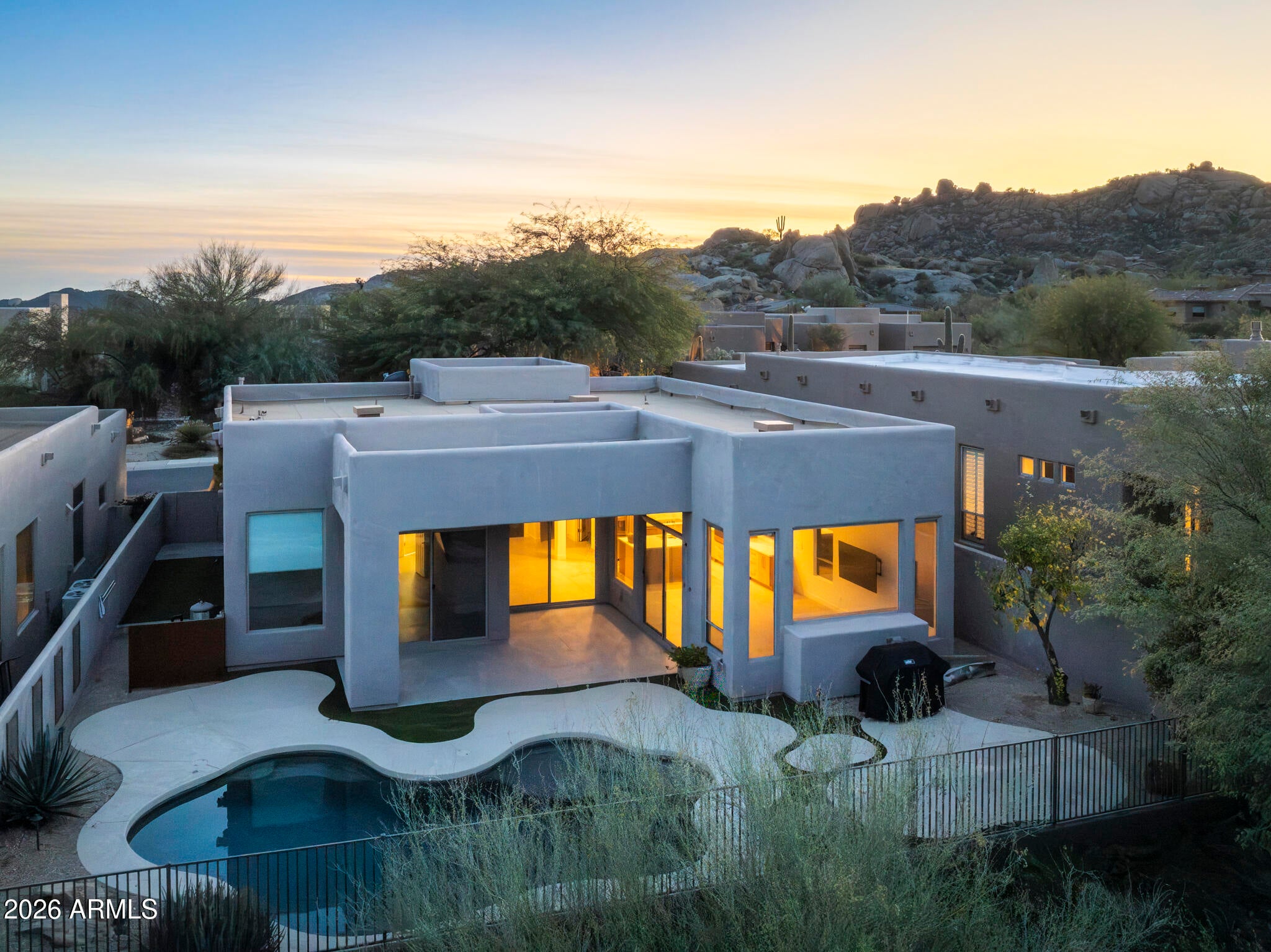 Set within the gated enclave of Pinnacle Canyon at Troon North, this residence offers refined desert living on a quiet cul-de-sac street. Clean, contemporary lines define the entry and continue through light-filled interiors with high ceilings, custom cabinetry, and expansive glass doors opening to resort-style patios and a private pool. The clean line kitchen features a generous quartz island and built-in wine fridge, while the primary suite provides a serene retreat with dramatic windows and a spa-inspired bath. Just minutes from world-class golf, hiking, and biking.