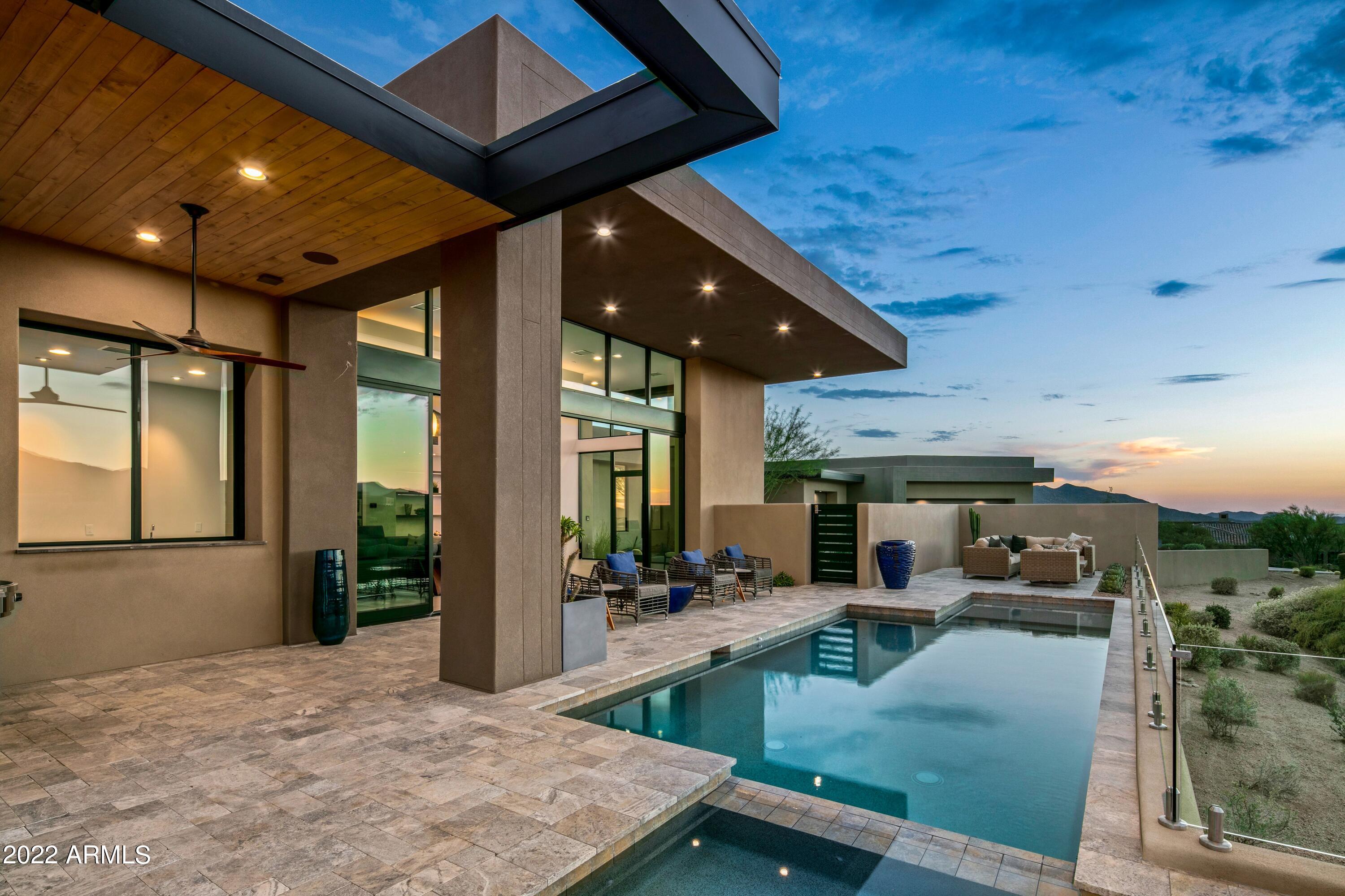 Available with Lifestyle or Golf Membership to Desert Mountain Club- Platinum Homes built this distinctive sleek Desert Mountain contemporary, an absolute dream home.  16' soaring ceilings and wall to wall windows makes it ideal for gazing at the Sonoran Desert's unfolding and ever-changing panoramic views of mountains, colorful sunsets and starry night skies.  The innovative architectural design creates a cultured contemporary living aesthetic:  open floor plan, clean lines, minimal clutter and a neutral color palette. Built in 2019 with organic materials, the home features clean angles, multiple roof lines, an open living floor plan, serenity and warmth, with a resort-like feel. The entrance sets the stage with the sound of water from the bubbling linear water features on both sides of the pavered entry path.  The sophisticated yet comfortable great room states impressionable artistic aspects: a floating Quartz hearth with linear lava rock fireplace and 12" X 24" tile surround to ceiling, floor to ceiling wall of windows including a 6-panel telescoping and pocketing wall system, and a dropped peninsula ceiling detail with ball shaped pendants and cove lighting. The comprehensive wet bar with wine columns and under counter refrigerator is the perfect connection for indoor/outdoor living.  The gourmet kitchen is art of its own.  High-end horizontal grain slab front cabinets, quartz counters with cutting edge acrylic full splash and oven hood, 18' stainless steel underlit shelf, spacious island with bar seating, Sub Zero, Wolf and Cove appliances and pot filler initiate the Chef's experience.  Move into the Butler's pantry between the dining space and kitchen and find another sink and faucet, banks of slab front cabinets, warming drawer, microwave and 36" refrigerator drawers.  An ensuite office or 4th bedroom, powder and laundry room confirm the elegant functionality of the open floor plan lifestyle. The private owner's suite opens to a breakfast bar, pocketing glass wall system to private outdoor space, seating area and double entries into the luxurious spa bath, creating an refuge of its own.  Note the separate vanities and opaque glass water closets, a free-standing Jacuzzi soaking tub backed by an inspiring accent wall of stainless-steel framed stone slab, a floor level walk-in shower with rain, wall, and handheld shower heads.  The two expansive designer closets are complete with drawers, shelves, racks, full length mirrors and stacked washer and dryer.  Up a few steps to the spacious guest entertainment lounge with bar, tv, seating area and game table for hours of enjoyment.  The two precisely appointed guest ensuites ensure a comfortable and enjoyable stay.  The Arizona outdoor living experience will delight by stepping into the Baja entry linear pool with spa and plexiglass fencing, Alfresco dining with the latest EVO grill, soaking up some sunshine or star gazing by the firepit. The lengthy pavered driveway and expansive motor court invite gatherings large and small.  An epoxy finished 3-car garage sports a walk-in golf closet with bag, club and shoe storage as well as ample additional storage.  The perfect near-the gate location within Desert Mountain allows quick access to town as well as to the 7 golf courses, 7 club houses, restaurants and hiking trails on the mountain. Regarding membership, Homeowner is willing to forfeit their Desert Mountain Club membership to Buyer. Buyer should contact Desert Mountain Membership staff for process details.