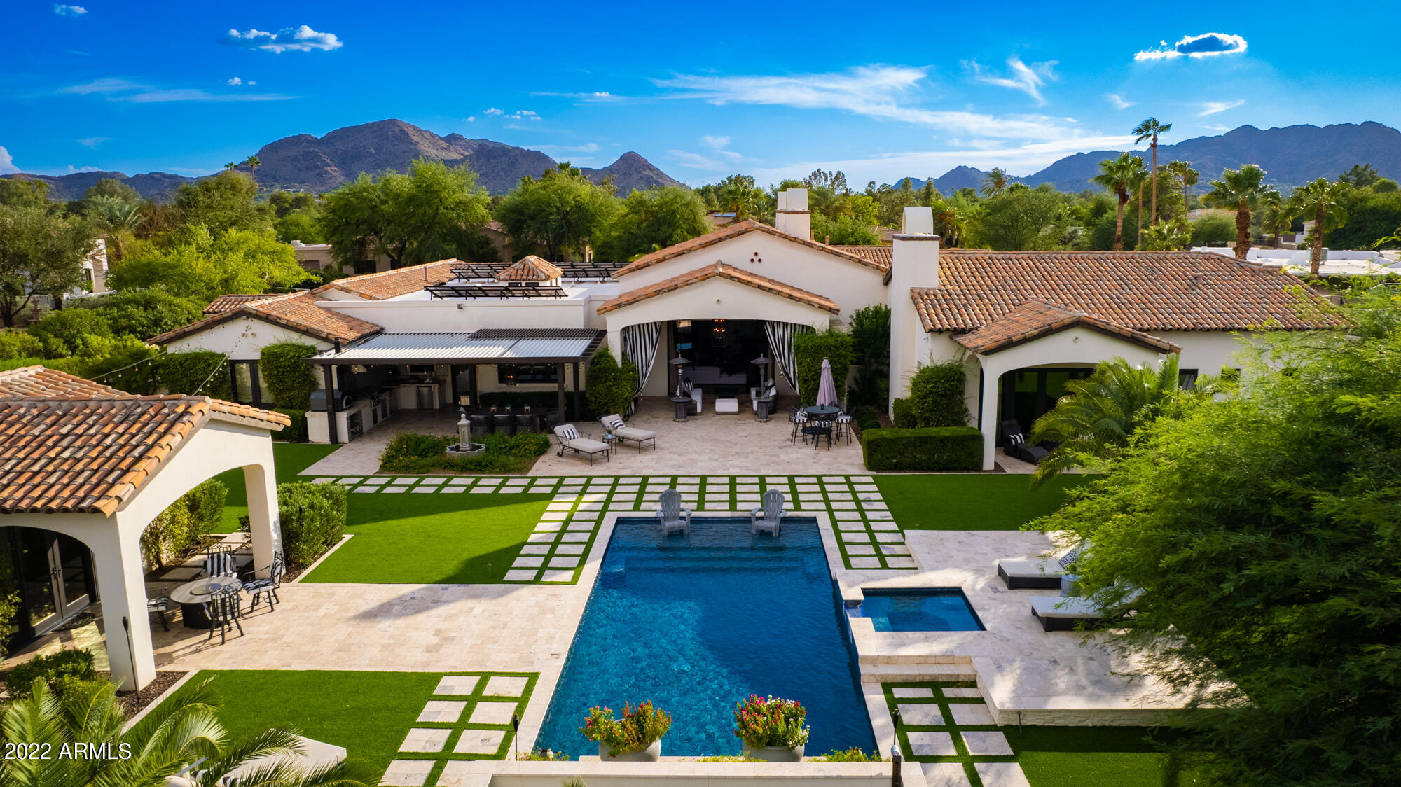 Beautifully designed custom Santorini home under 6,800 sq.ft., on a quiet cul-de-sac lot in Paradise Valley. Single level, split floor plan w/ detached guest casita/ pool house. The main house features 5 en suite bedrooms, 5 1/2 baths & 4 fireplaces. A separate office w/ mountain views from patio, in addition to a game room w/ patio leading to lighted sports court & batting cage. Magnificent bonus structure (approx.1,200 sq.ft., not included in home sq. ft.) is currently a 4+ car showroom, climate controlled, with loft storage and AV system. This structure could easily be converted into larger guest house, massive gym, etc. Dining room is complete with temperature controlled, 400 bottle wine wall and French doors leading to pergola outdoor space - great for entertaining. Be surprised by.. Be surprised by the captivating floor plan and interior, with Chefs kitchen (wolf & sub zero appliances), butler bar, large electric pocket doors leading to resort style back yard. The impressive primary suite includes 2 separate closets, vanities and water closets. The primary bath also showcases a large soaking tub, grand steam shower and spectacular stone and marble finishes through out. The estate also features extensive Crestron /Lutron home automation system. Including outdoor lighting and speakers throughout the property. A perfect entertainers dream with covered outdoor kitchen, complete with special "Chicago Brick" pizza oven. The owned solar panels and lush synthetic turf both front and back make this a very efficient, cost effective and low maintenance home. Lavish & spacious outdoor areas, Beadcrete pool, baja shelf and raised spa, paired with a quiet Paradise Valley private location, create the ideal living concept... perfect for enjoying the best of Arizona's Indoor/Outdoor Living.