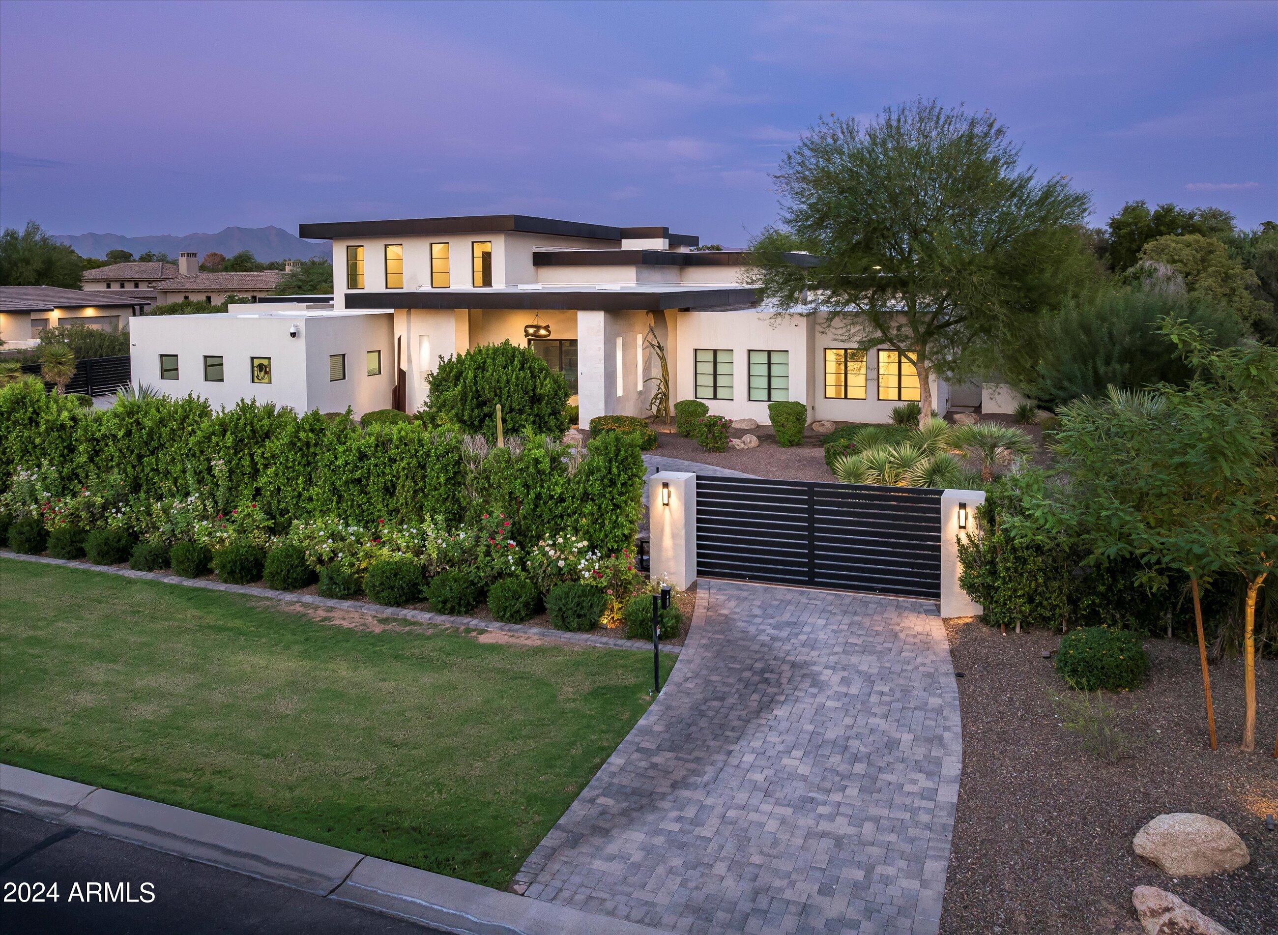 Welcome to this privately gated modern luxury estate, set on 1+  acres in the heart of Paradise Valley. Designed for the discerning buyer, this residence offers expansive ceilings & abundance of natural light throughout. Featuring a 30'+ pocket door for true indoor/outdoor living open to the huge covered patio. Wide open floor plan leads to a secluded primary retreat with a private office, steps from sparkling pool & spa. An entertainer's dream, the home boasts an impressive kitchen with a separate prep kitchen, plus an outdoor kitchen & bar for alfresco dining. Spacious ensuite guest bedrooms, large upstairs great room/game room area, a private theatre, a separate guesthouse with garage, pool house, workout room & multi-sport court offering tennis, pickleball & full court basketball.