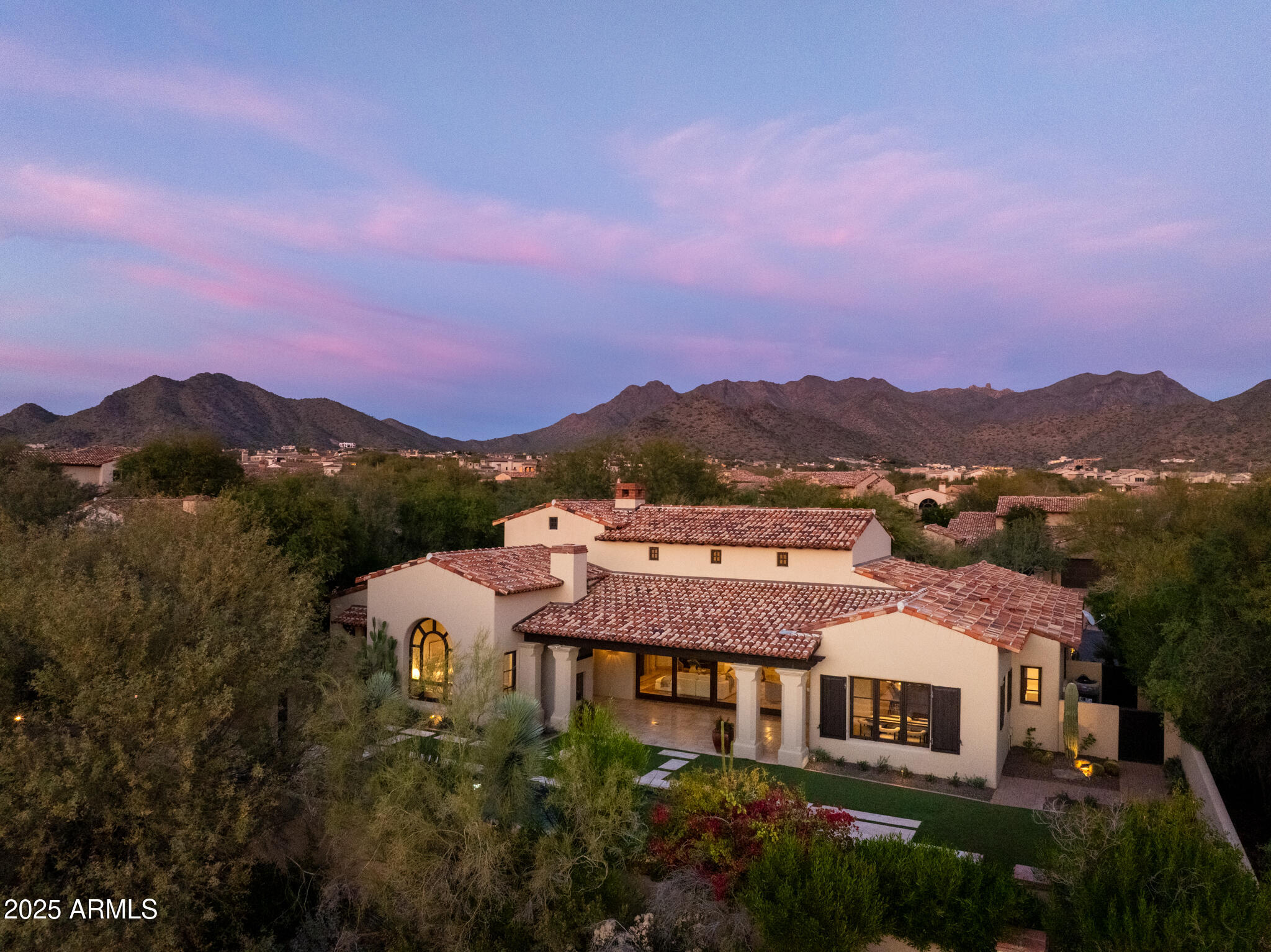 Located in one of Silverleafs most sought-after guard-gated enclaves, this single-level residence blends timeless architecture with effortless indoor-outdoor living. A rose-lined front courtyard framed by mountain views creates a composed sense of arrival. Custom steel and glass casement doors open to a light-filled great room with clerestory windows and expansive walls of glass that extend to a deep covered patio anchored by a floor-to-ceiling fireplace. Outdoor living continues at a BBQ ramada and spa-side fire pit designed for relaxed entertaining. The kitchen is thoughtfully appointed with a scullery and an adjacent, fully equipped bar. Three ensuite bedrooms, a private office offer quiet retreat, complemented by a heated pool and spa, with walkable access to the Silverleaf Clubhouse.