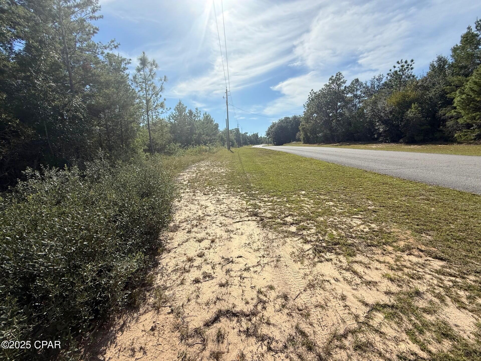Nestled along a paved road in the Sunny Hills community, this wooded lot provides the ideal backdrop for your future dream home! Enjoy community amenities such as an 18-hole golf course, the picturesque Boat Lake, and a variety of nearby fishing opportunities. Just 43 miles from Panama City Beach, famous for its sugar-white sand and emerald waters, you'll experience the tranquility of small-town living with easy access to one of Florida's top coastal destinations. Adjoining lot for sale also.