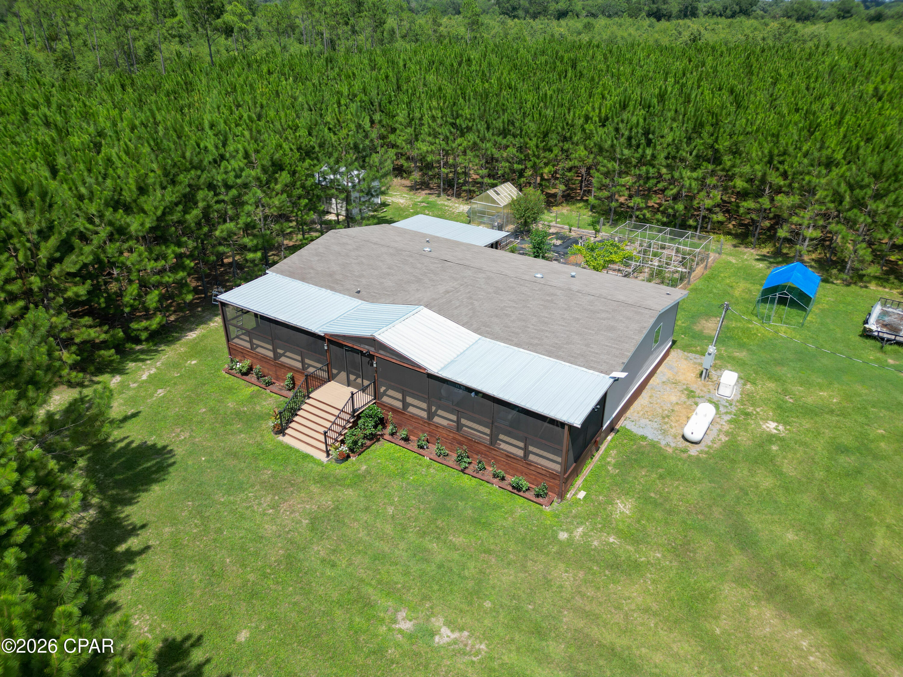 Welcome to 4268 Rogers Road in Greenwood, where comfort, privacy, and country living come together. A tree-lined private drive leads to this fenced property with an electric entry gate and a well-appointed 2022 double-wide mobile home. Inside, the spacious open-concept living area is ideal for everyday living and entertaining. The kitchen is truly a chef's dream, complete with stainless steel appliances, a French-door refrigerator, double ovens, a farmhouse sink, and a large island offering plenty of workspace and seating. The generously sized primary suite includes a private bathroom with a double vanity, soaking tub, and separate shower. Outside, the property offers an impressive list of features, including a large greenhouse, chicken coop with an attached run, and a generator for added peace of mind. An oversized screened porch provides the perfect place to create a comfortable outdoor lounge, entertain guests, or simply relax and enjoy the peaceful surroundings.